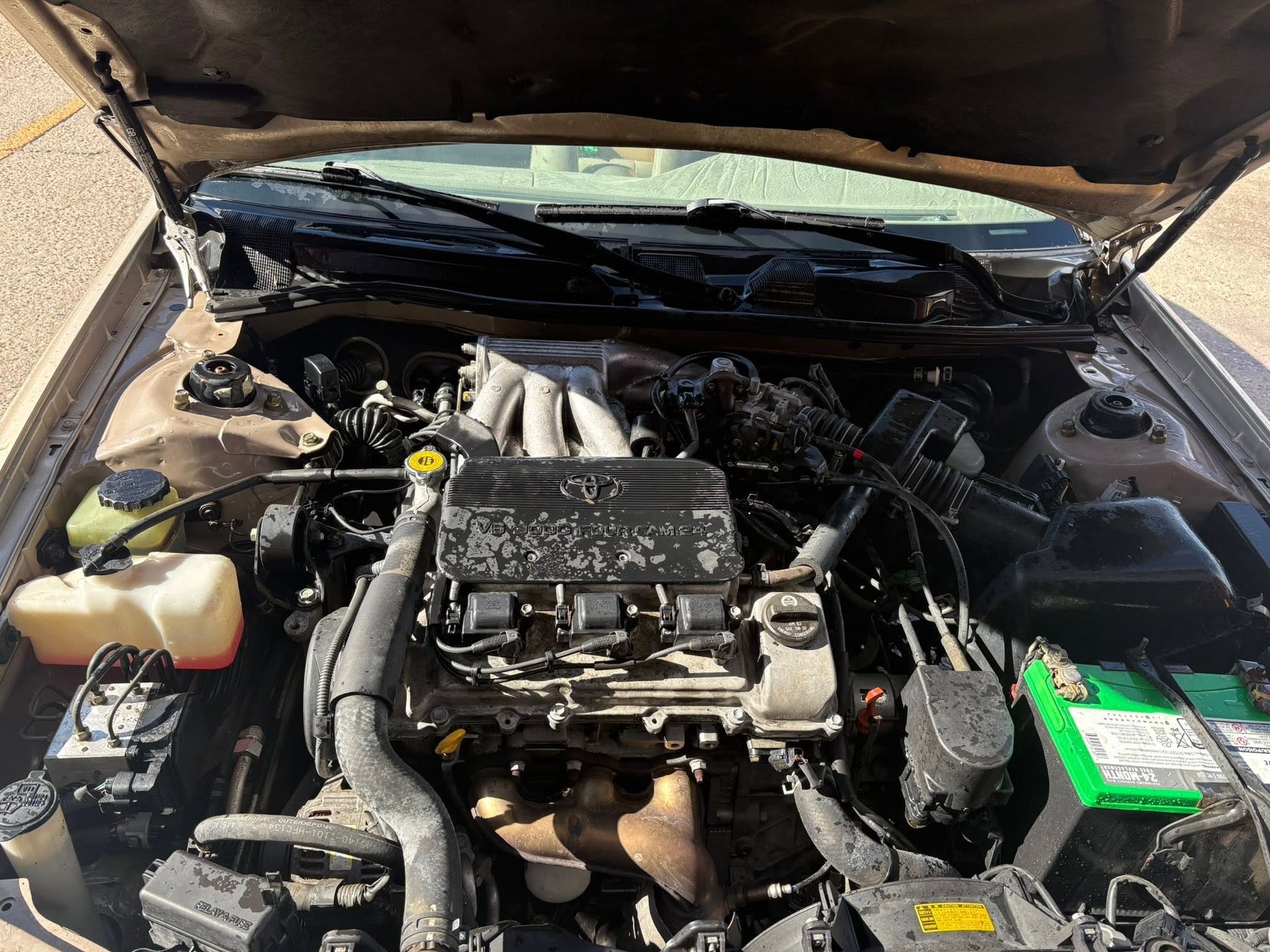 Car engine bay with hood open, showing battery, hoses, and engine components| Sonny's Automotive Repair and Sales