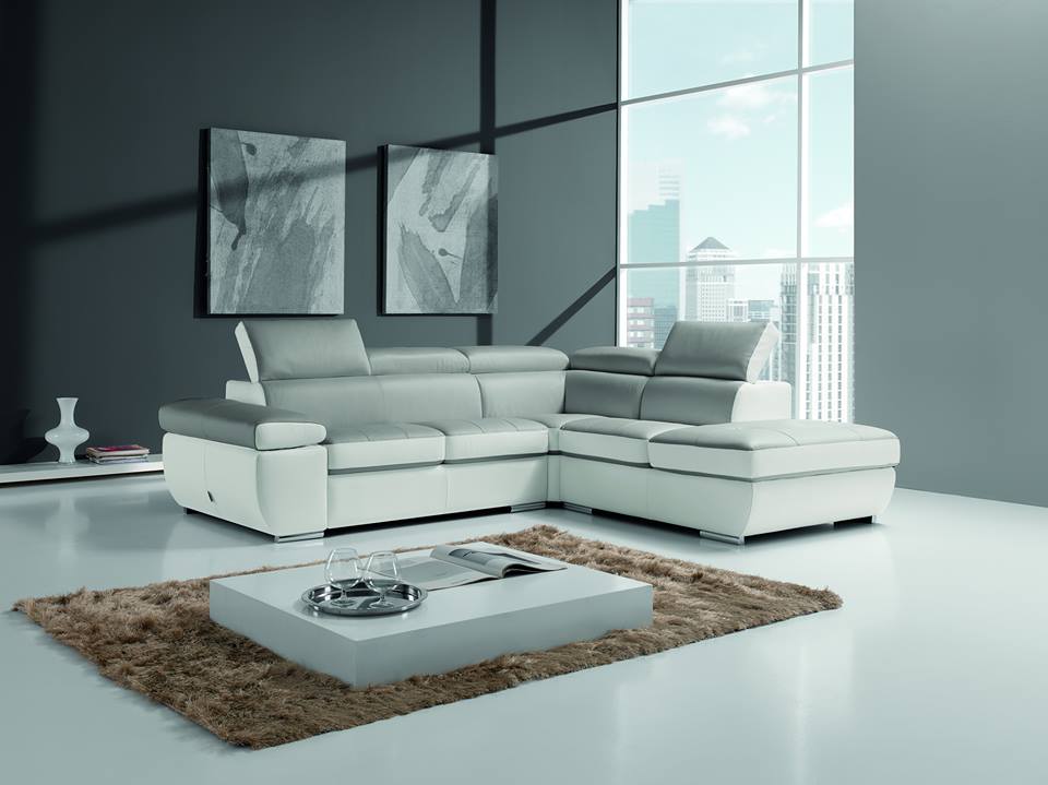 Divano componibile moderno bianco e grigio in un soggiorno minimalista con vista sulla città e tavolino da caffè.