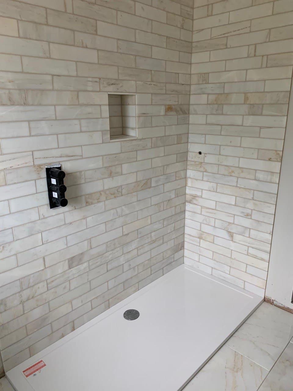 This is a photo of a kitchen splash back that has been tiled in black and grey. It is installed in between the hob and extractor. The photo was taken around Brighton East Sussex UK