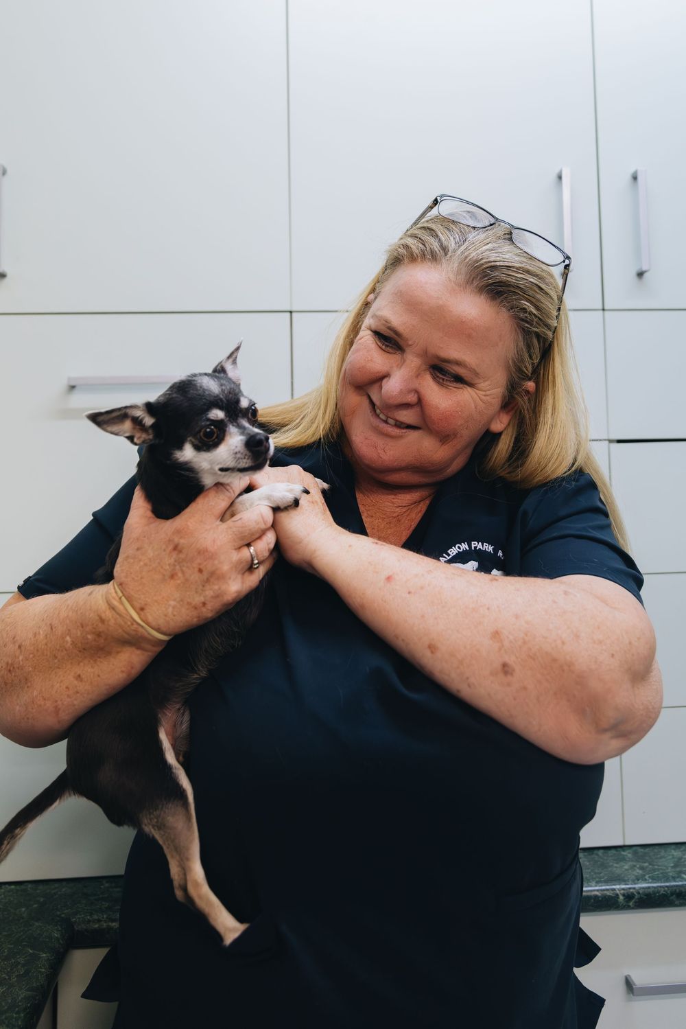 A woman is holding a small dog in her arms.