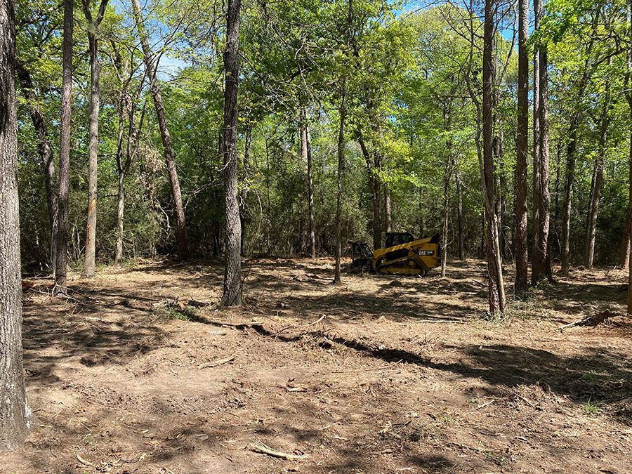 Wooded trail with a yellow off-road vehicle in the background under green trees