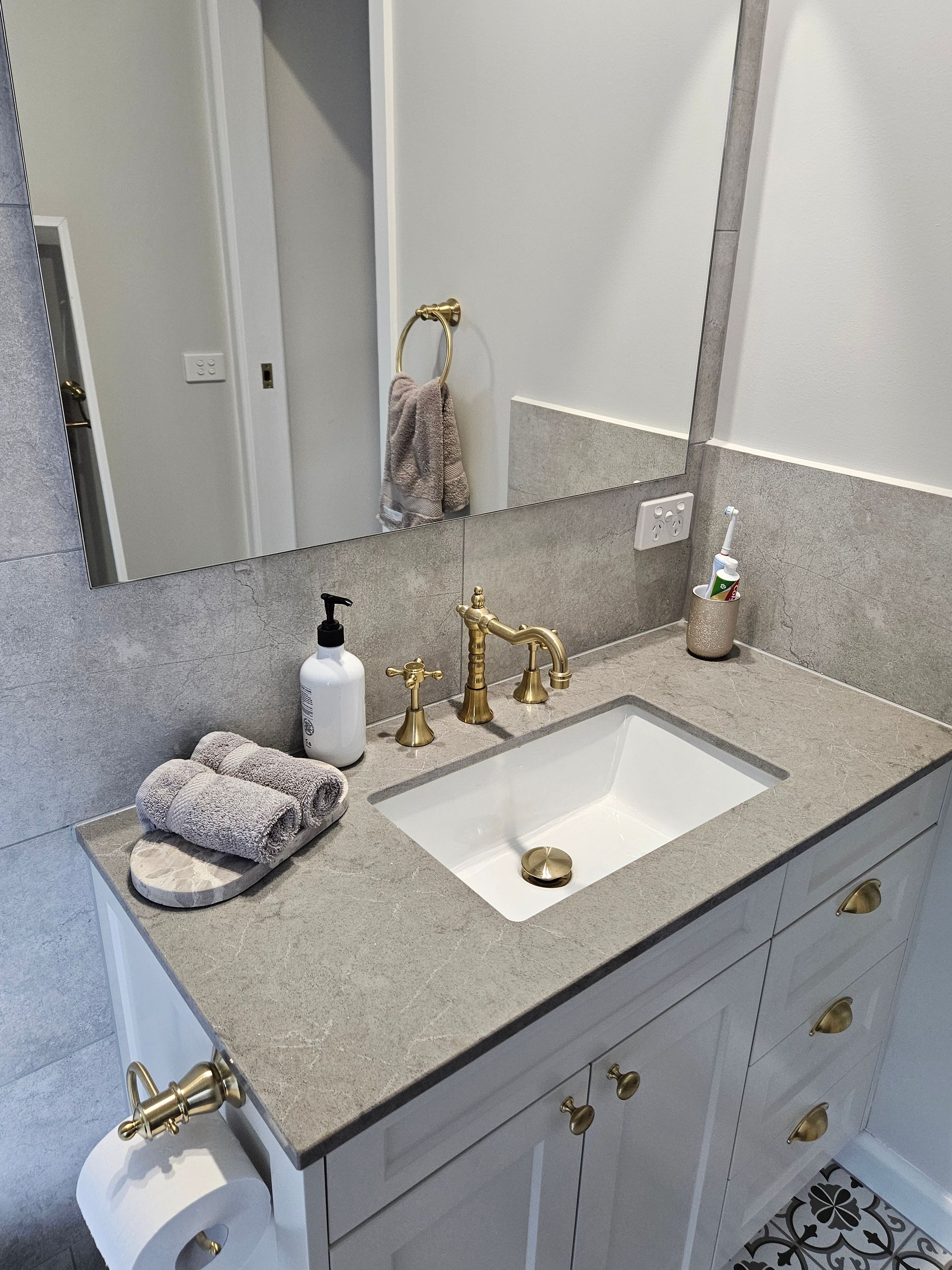 A bathroom with a sink , mirror , and towels on the counter.