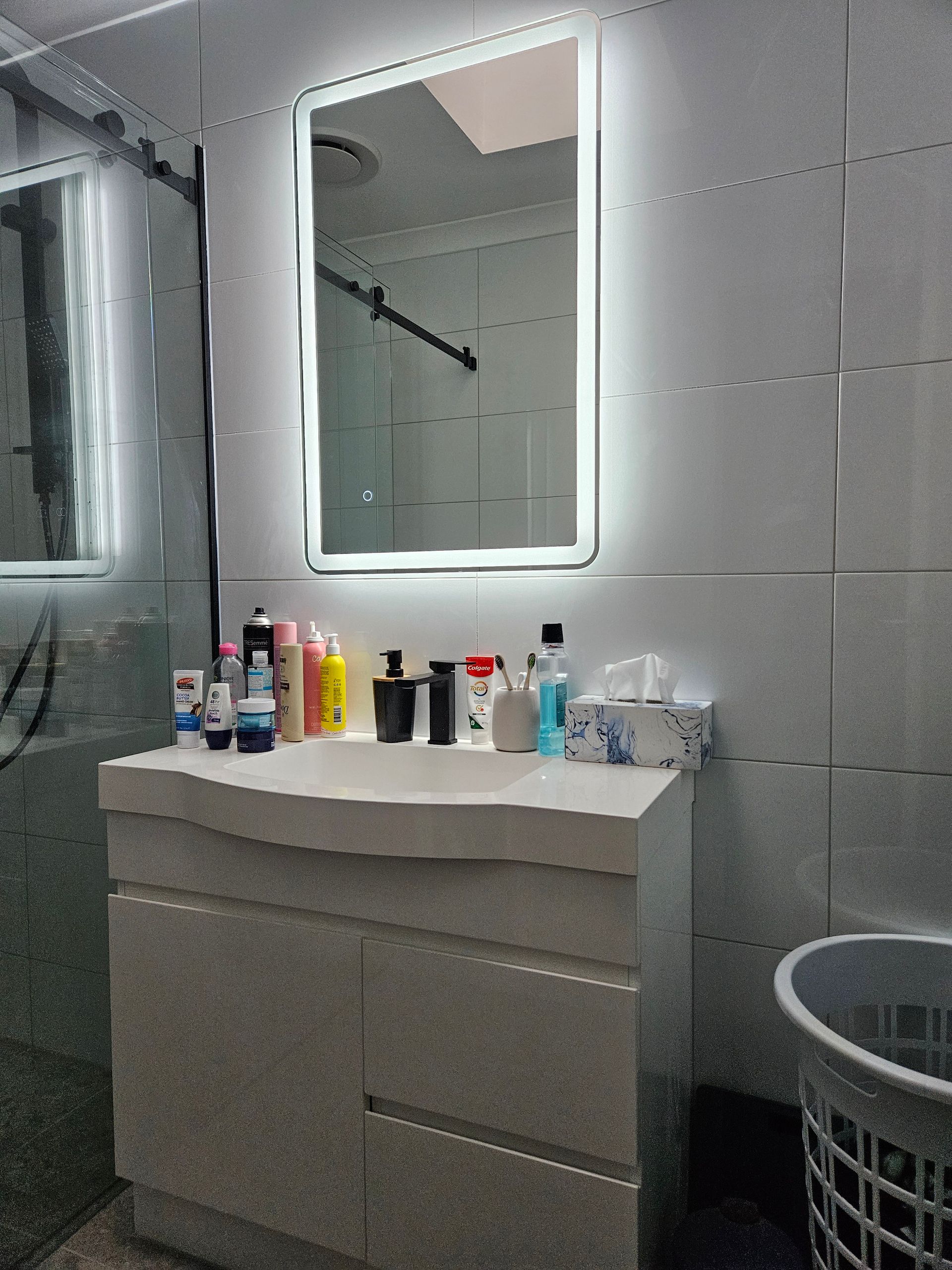A bathroom with a sink , mirror and laundry basket