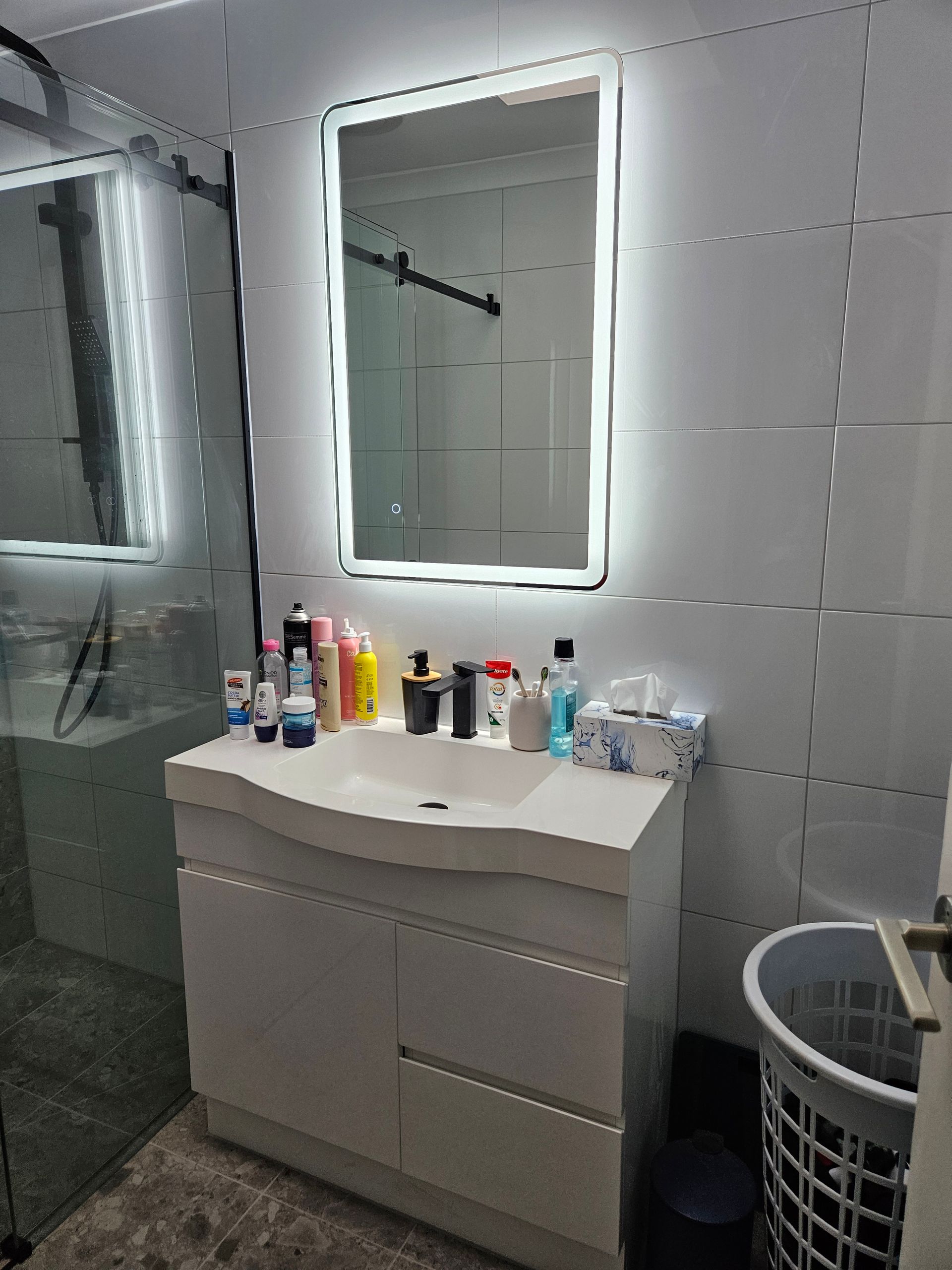 A bathroom with a sink , mirror , and laundry basket.