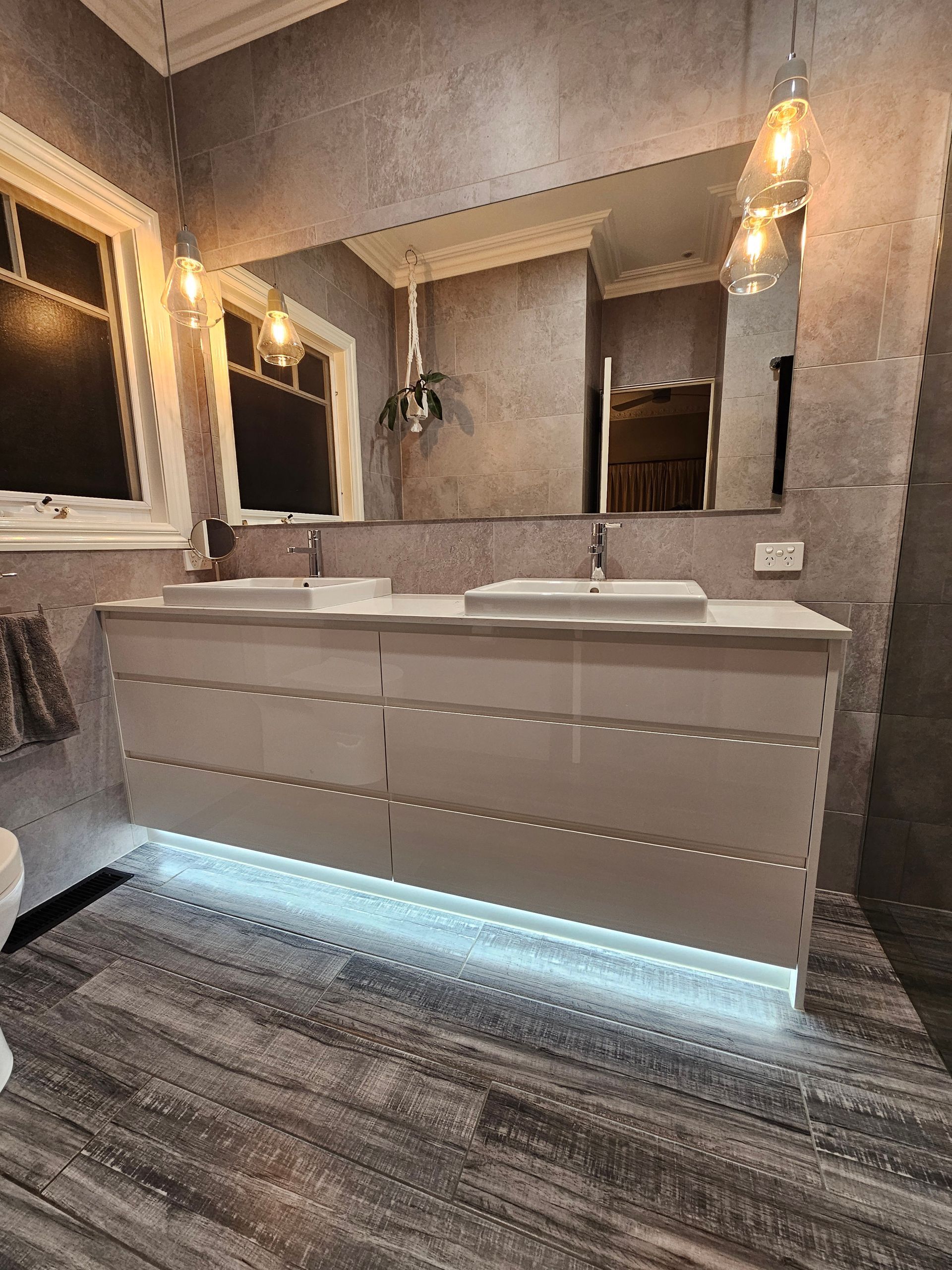 A bathroom with two sinks , a mirror and a toilet.