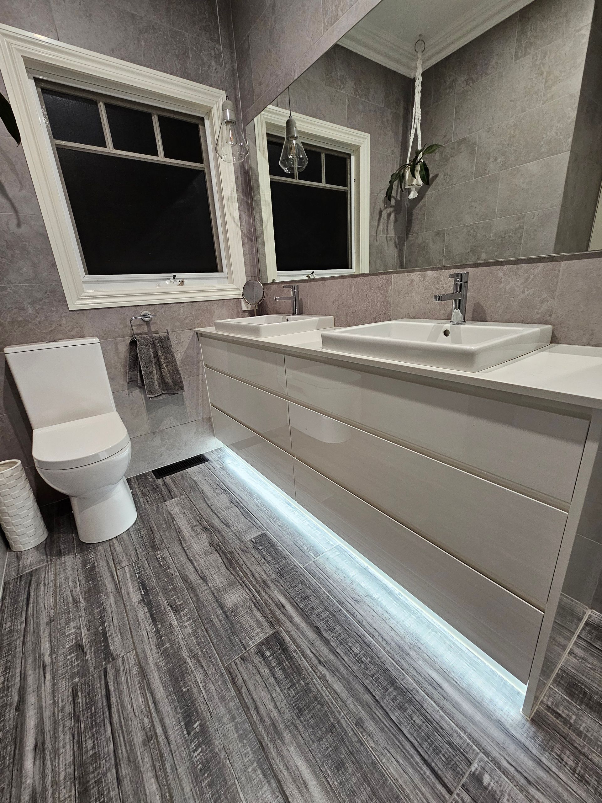 A bathroom with two sinks , a toilet and a mirror.