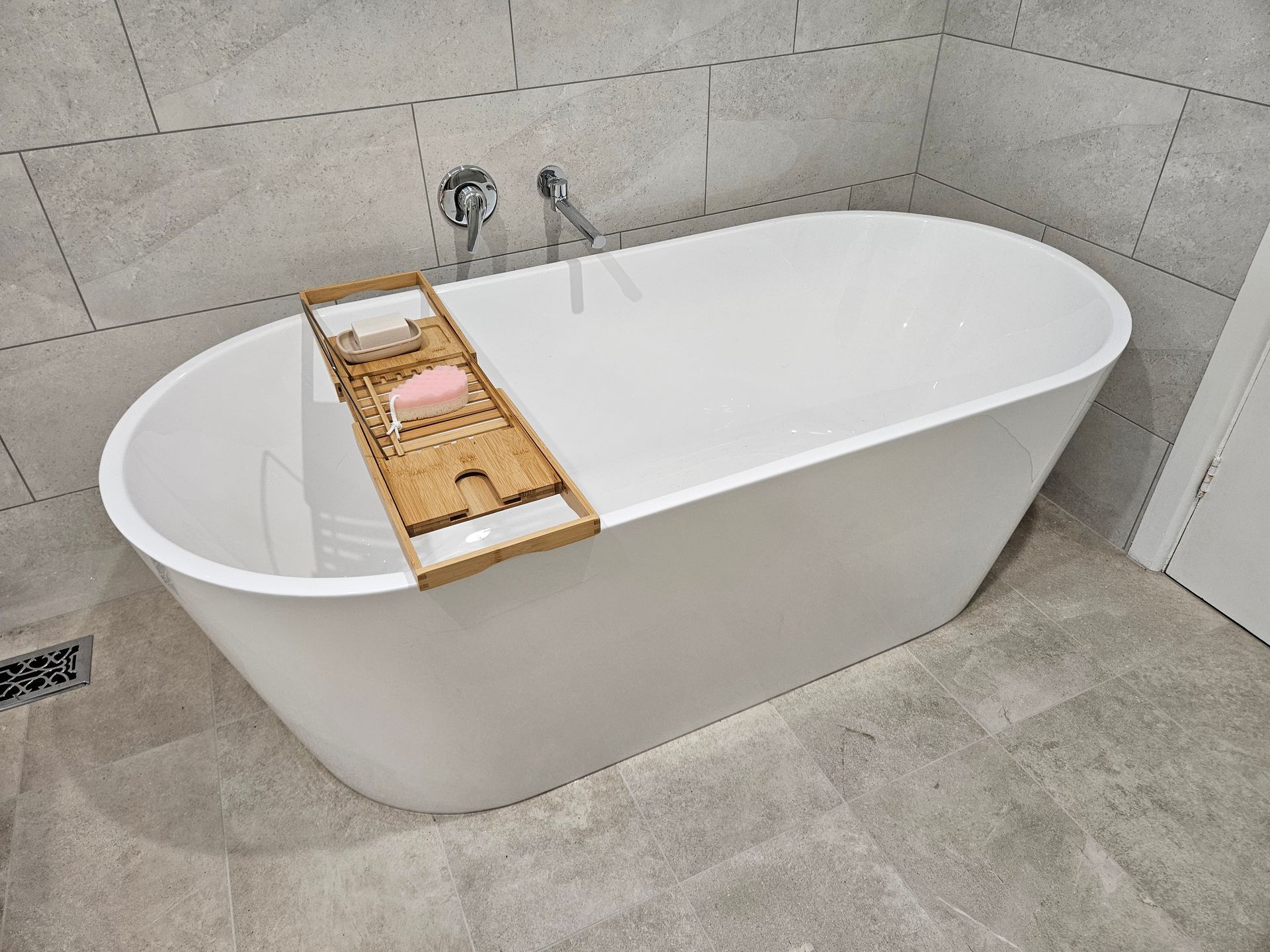 A white bathtub with a wooden tray on top of it in a bathroom.