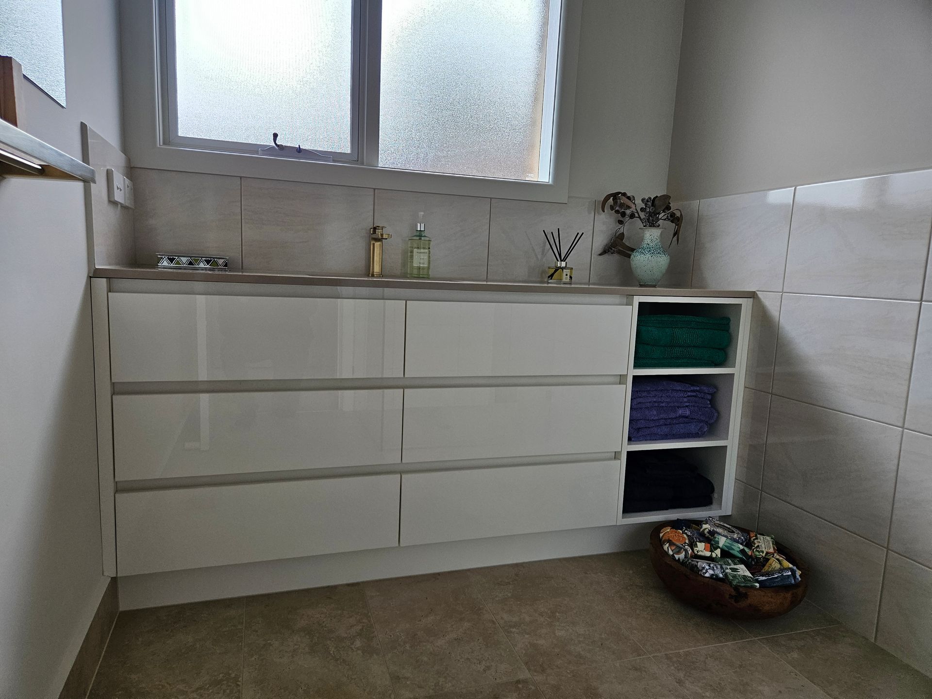 A bathroom with white cabinets , a sink and a window.