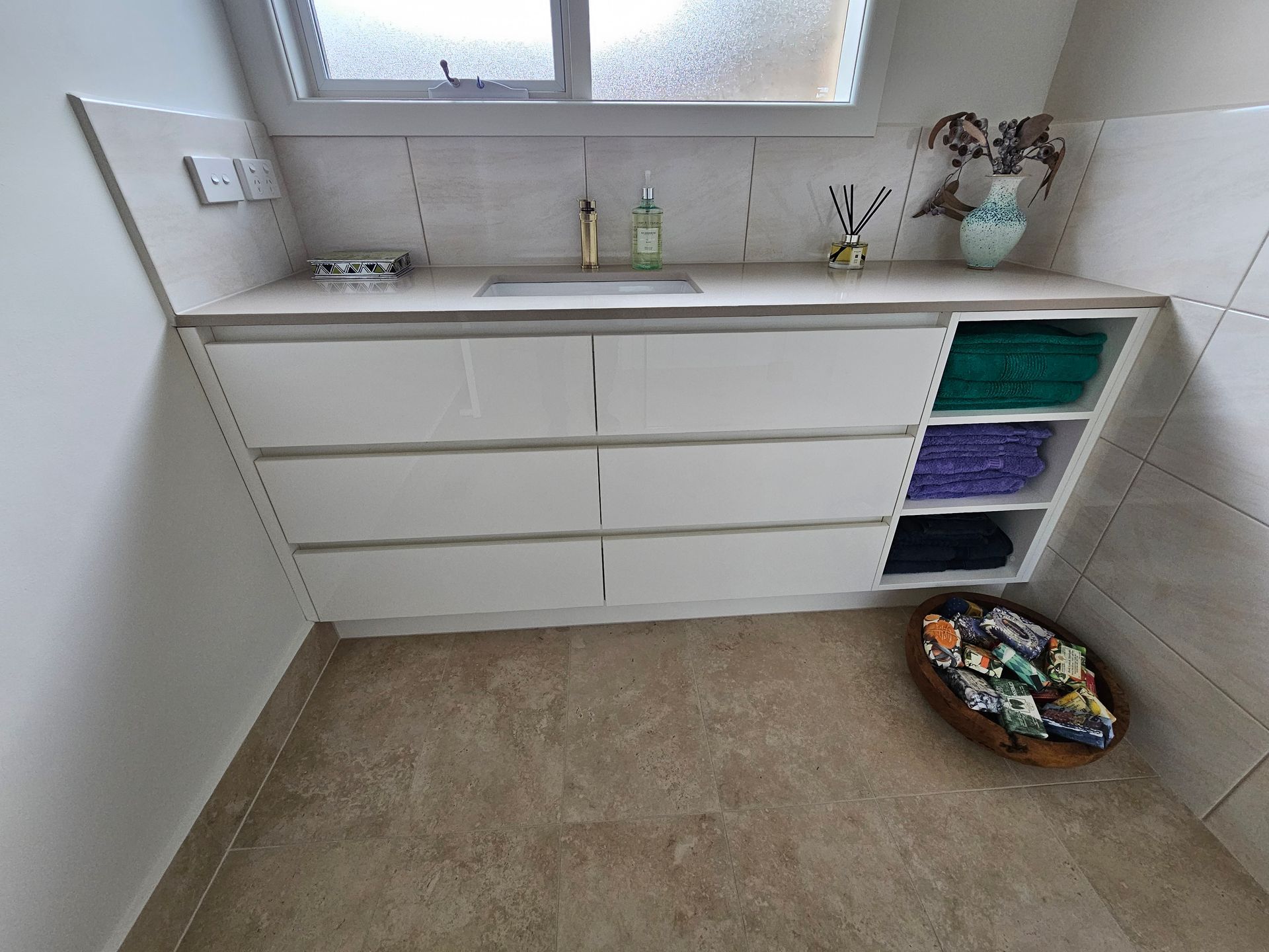 A bathroom with a sink and a basket of towels on the floor.