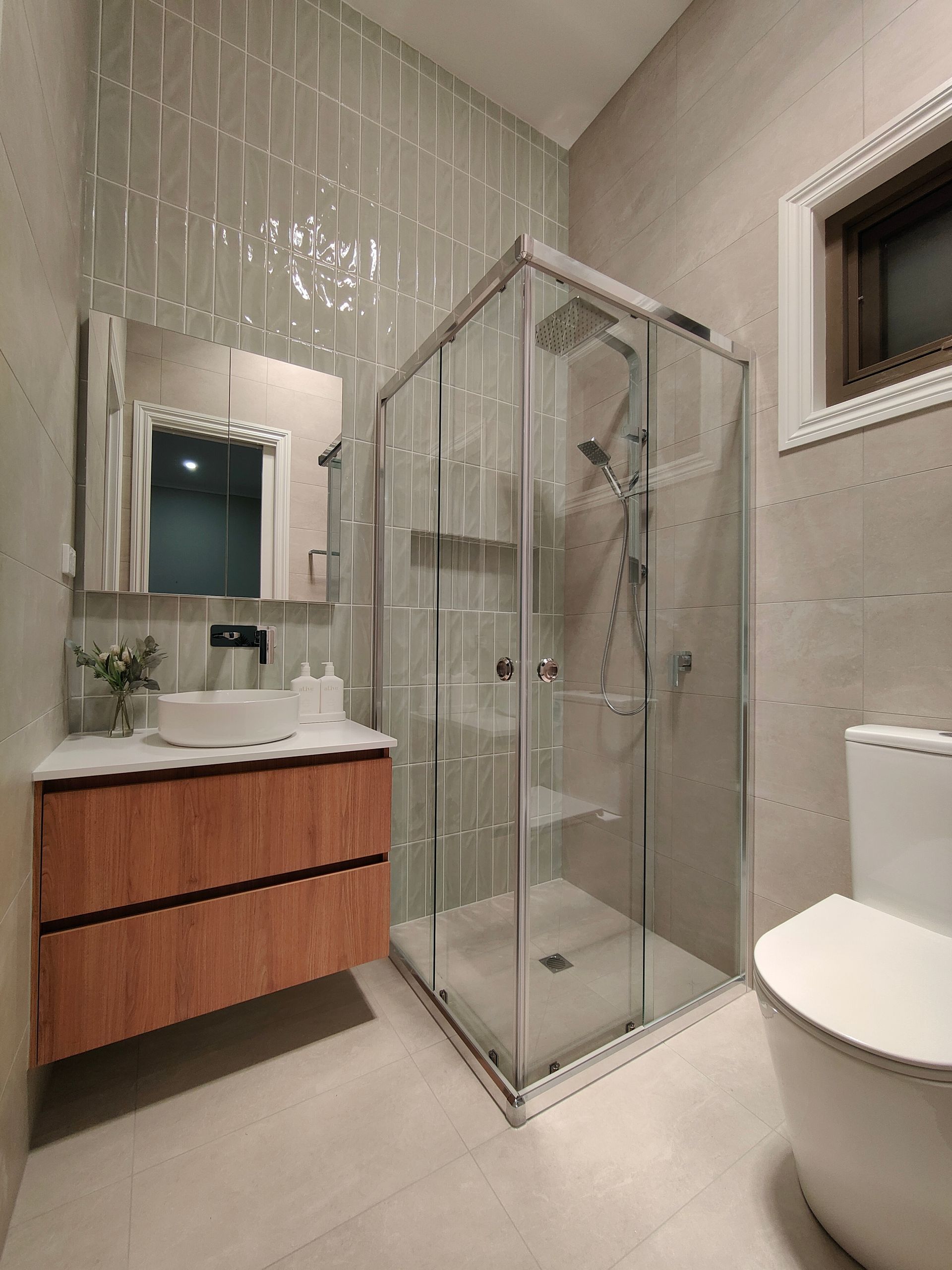 A bathroom with a toilet , sink , shower and mirror.