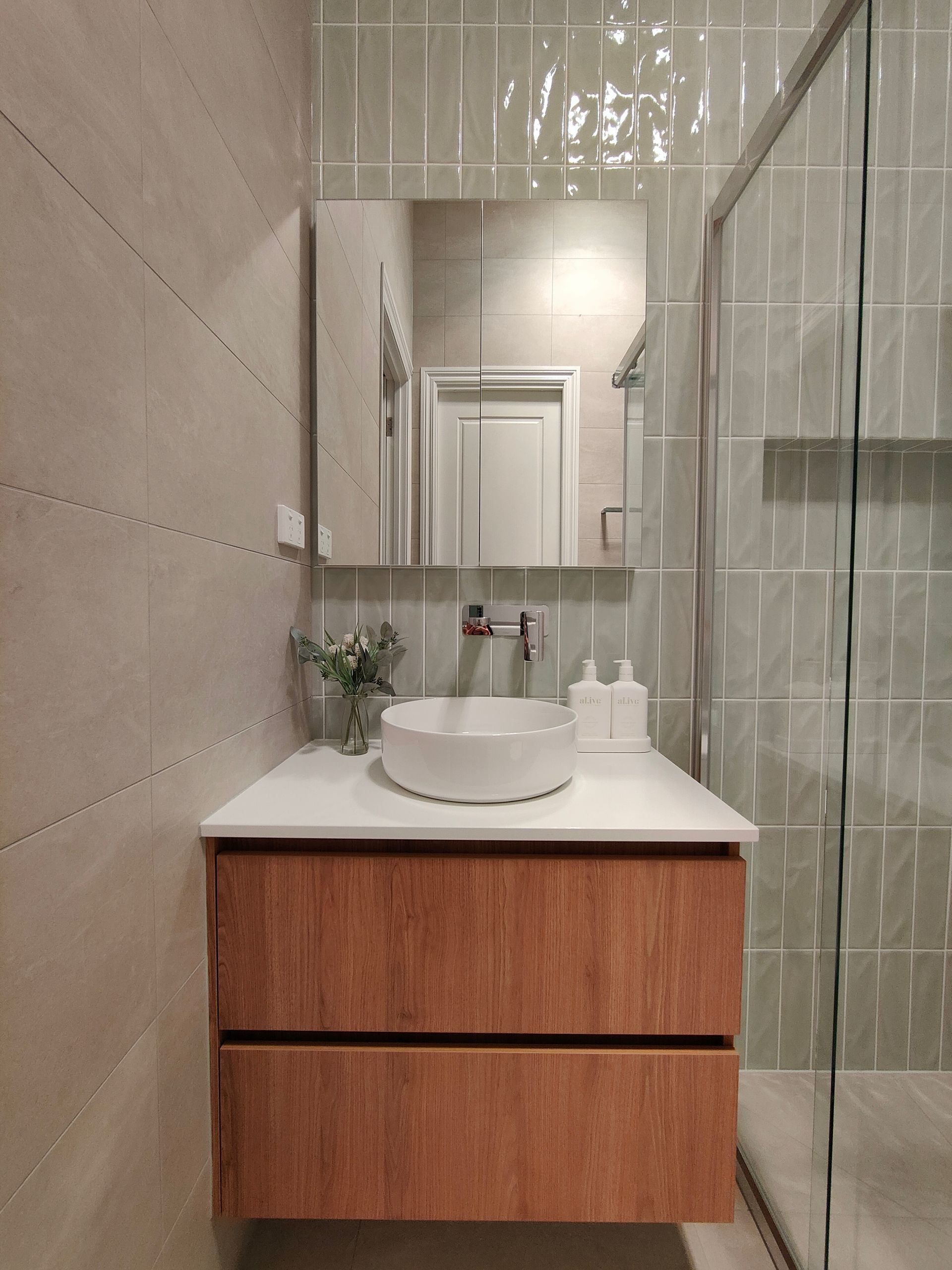 A bathroom with a sink , mirror and shower.