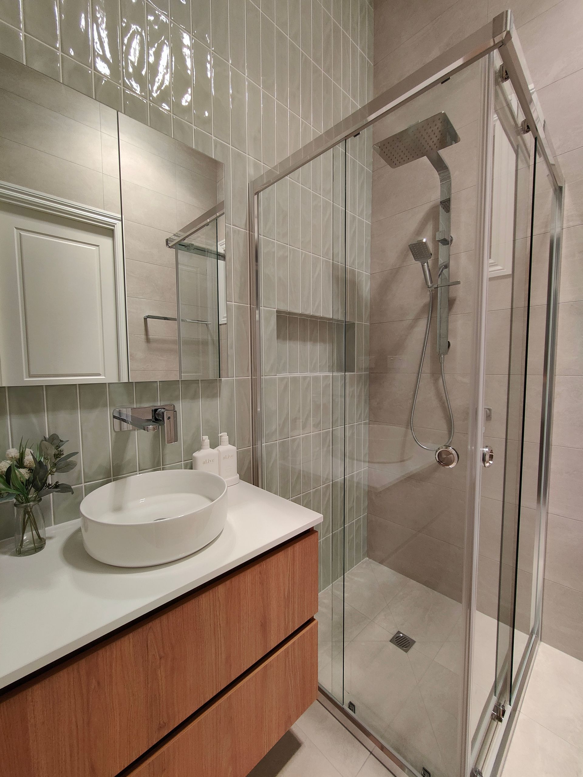 A bathroom with a sink and a shower with sliding glass doors.