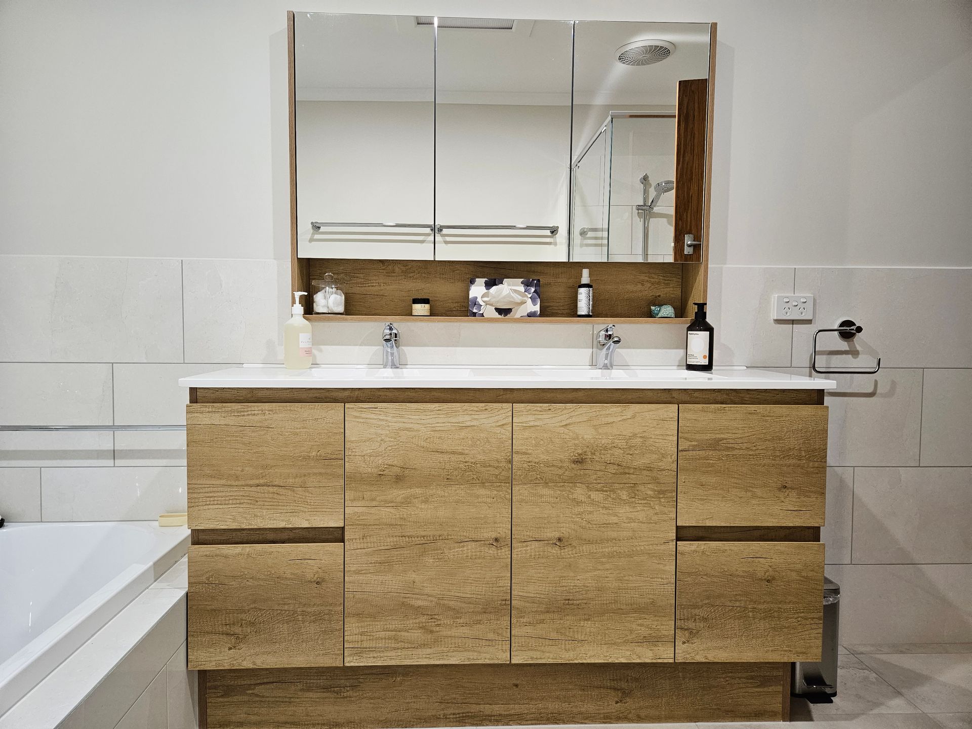 A bathroom with two sinks , a mirror and a bathtub.