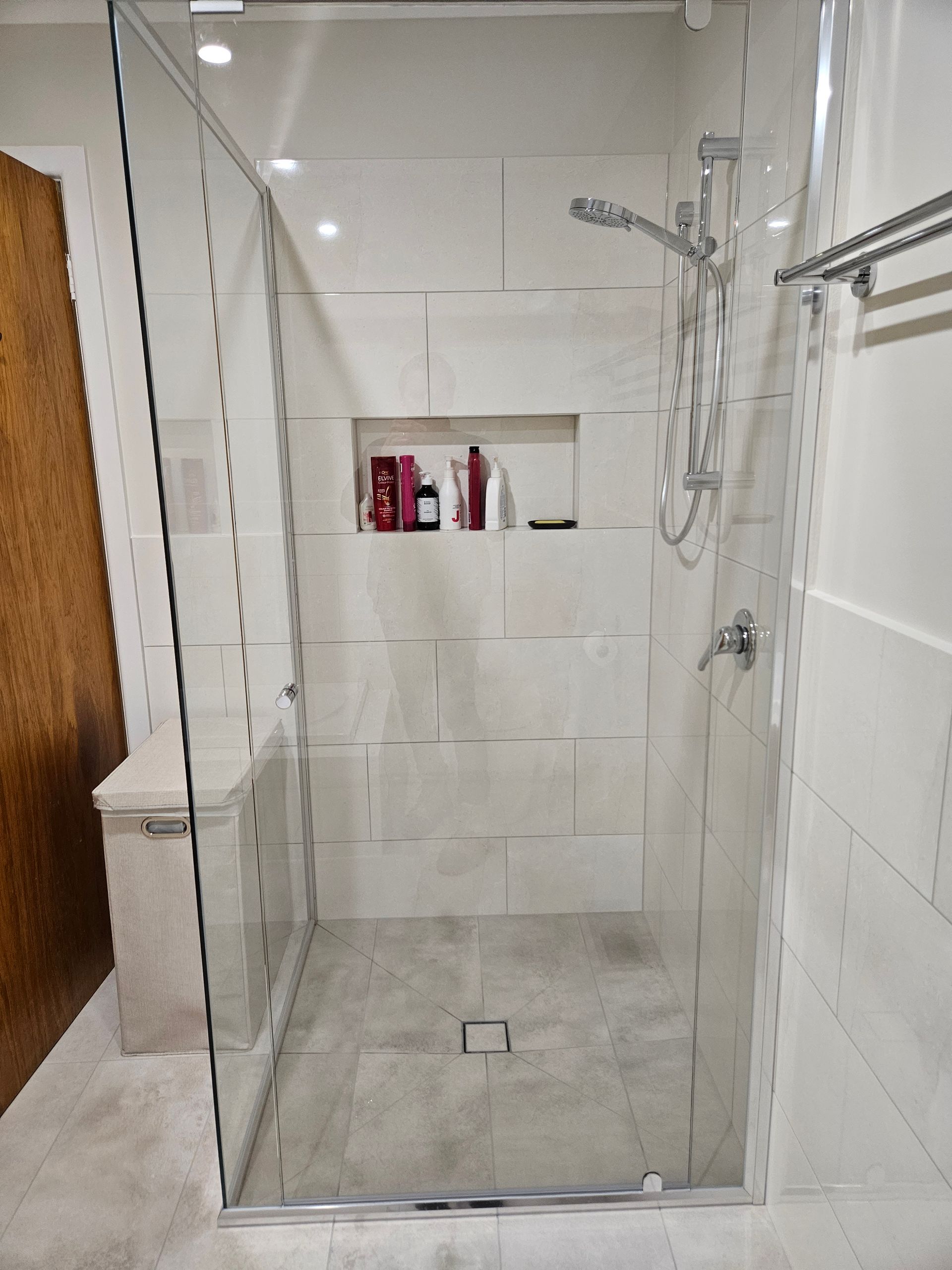 A bathroom with a walk in shower with a glass door.