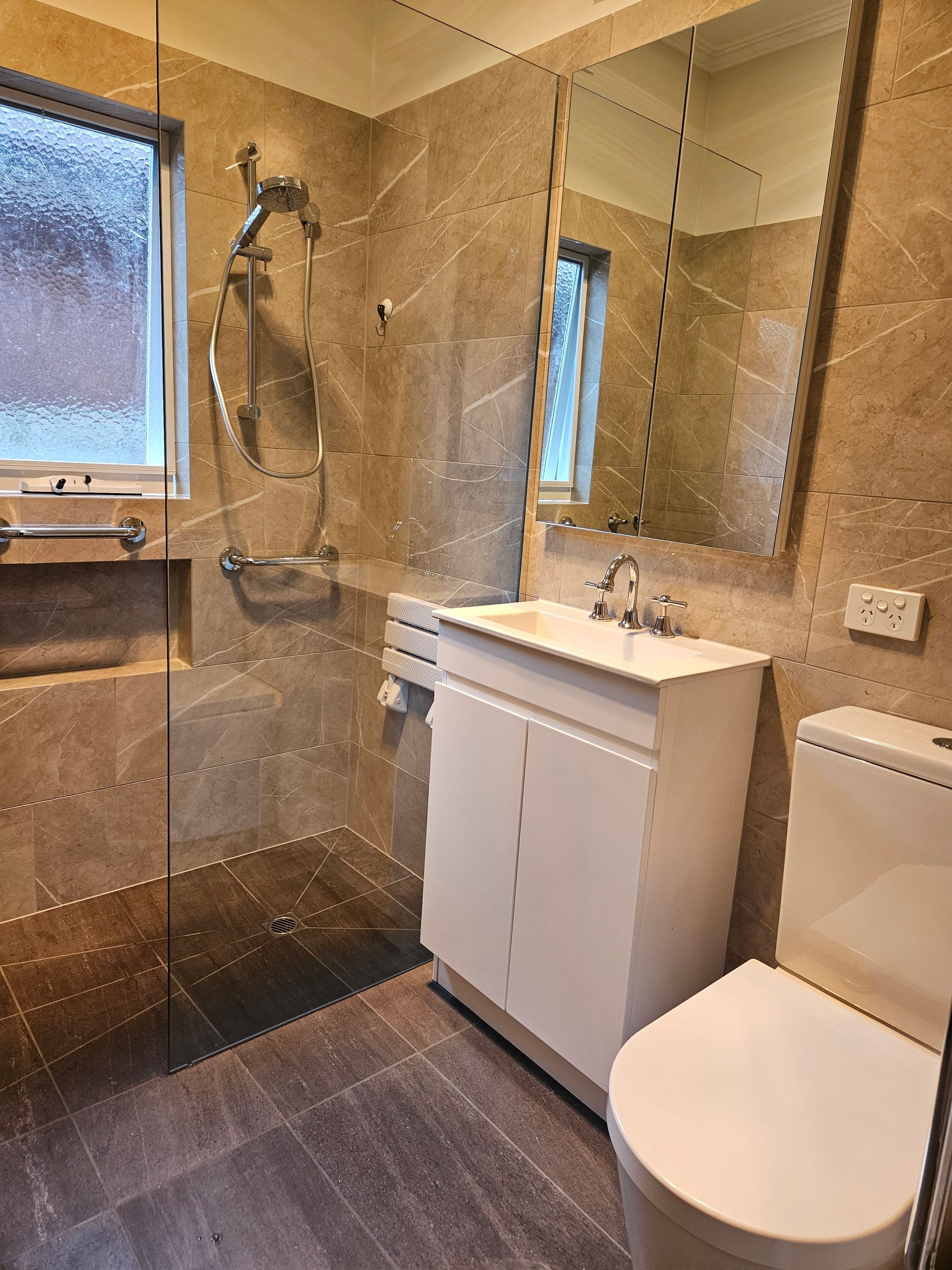 A bathroom with a toilet , sink , shower and mirror.