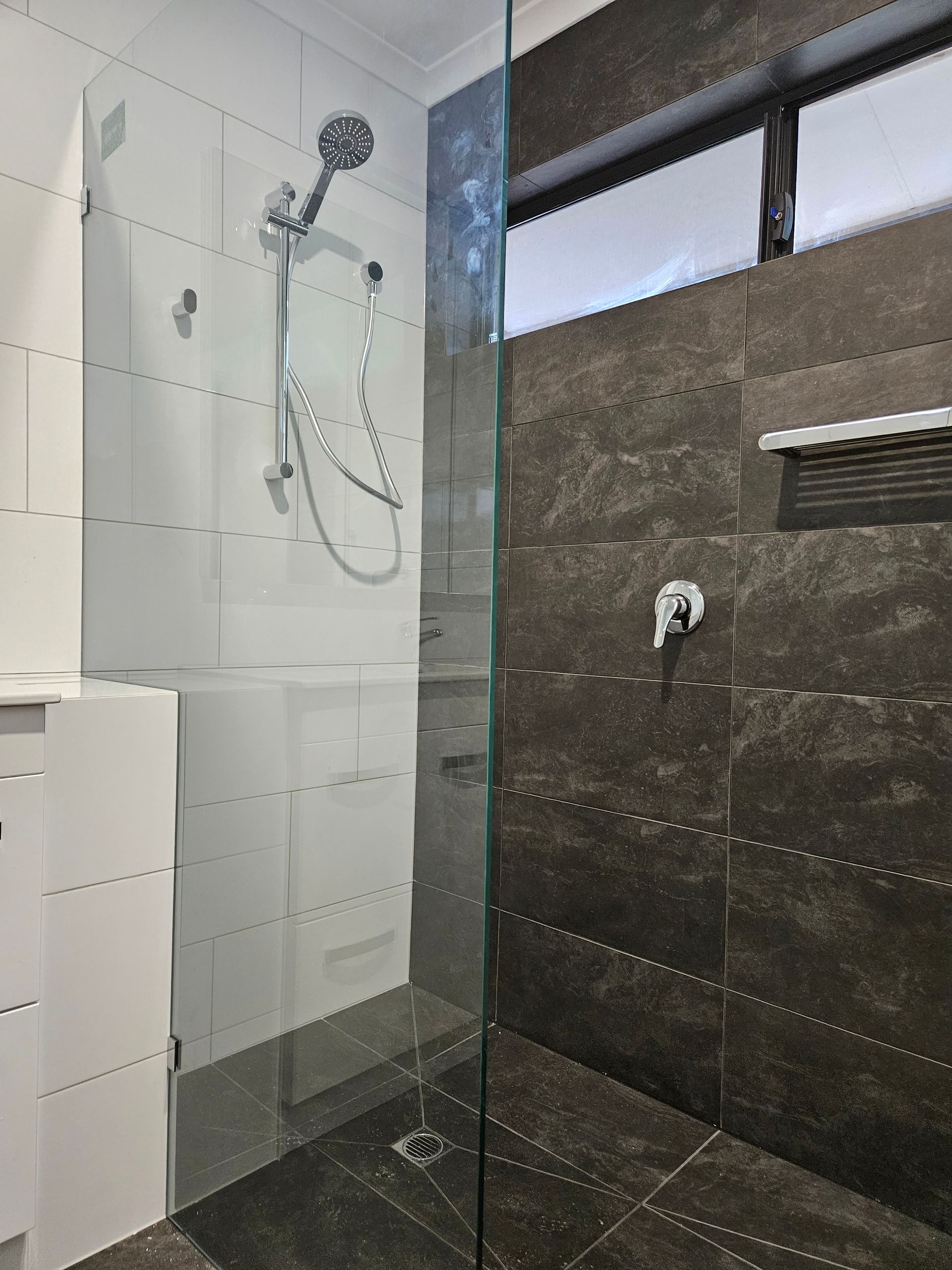 A bathroom with a walk in shower with a glass door.