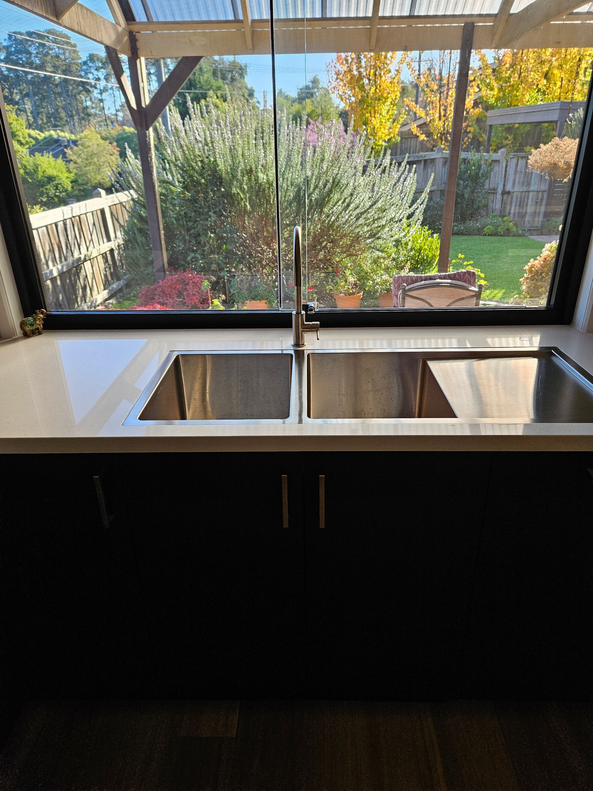 A kitchen sink with a view of a garden through a window