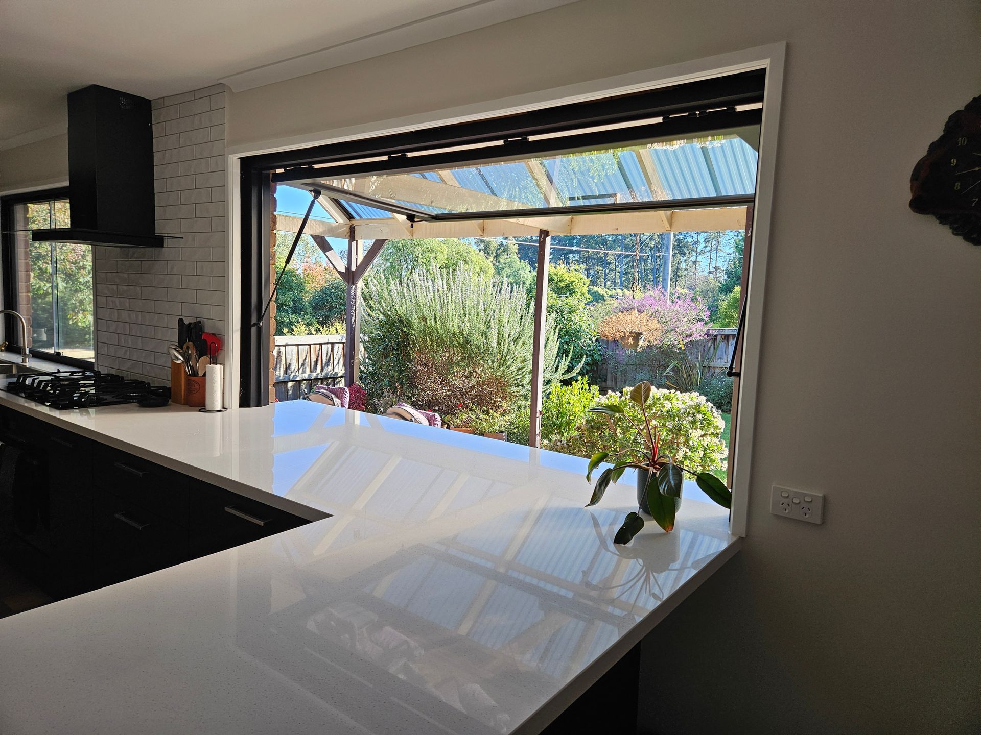 A kitchen with a large window and a plant on the counter.