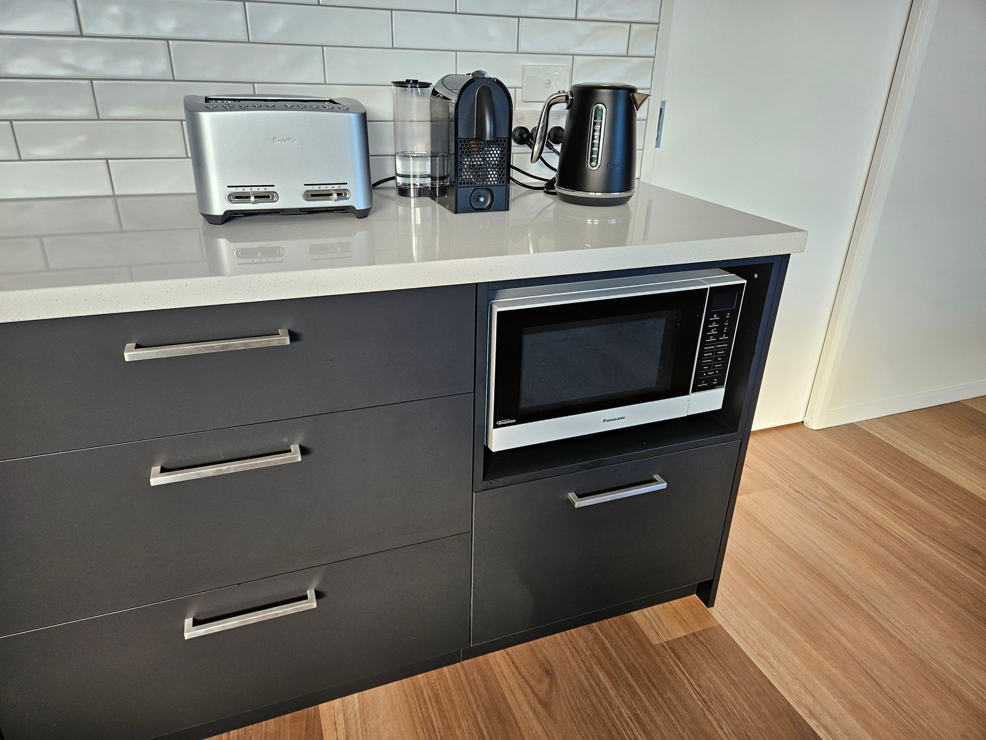 A kitchen counter with a microwave , toaster , and kettle on it.