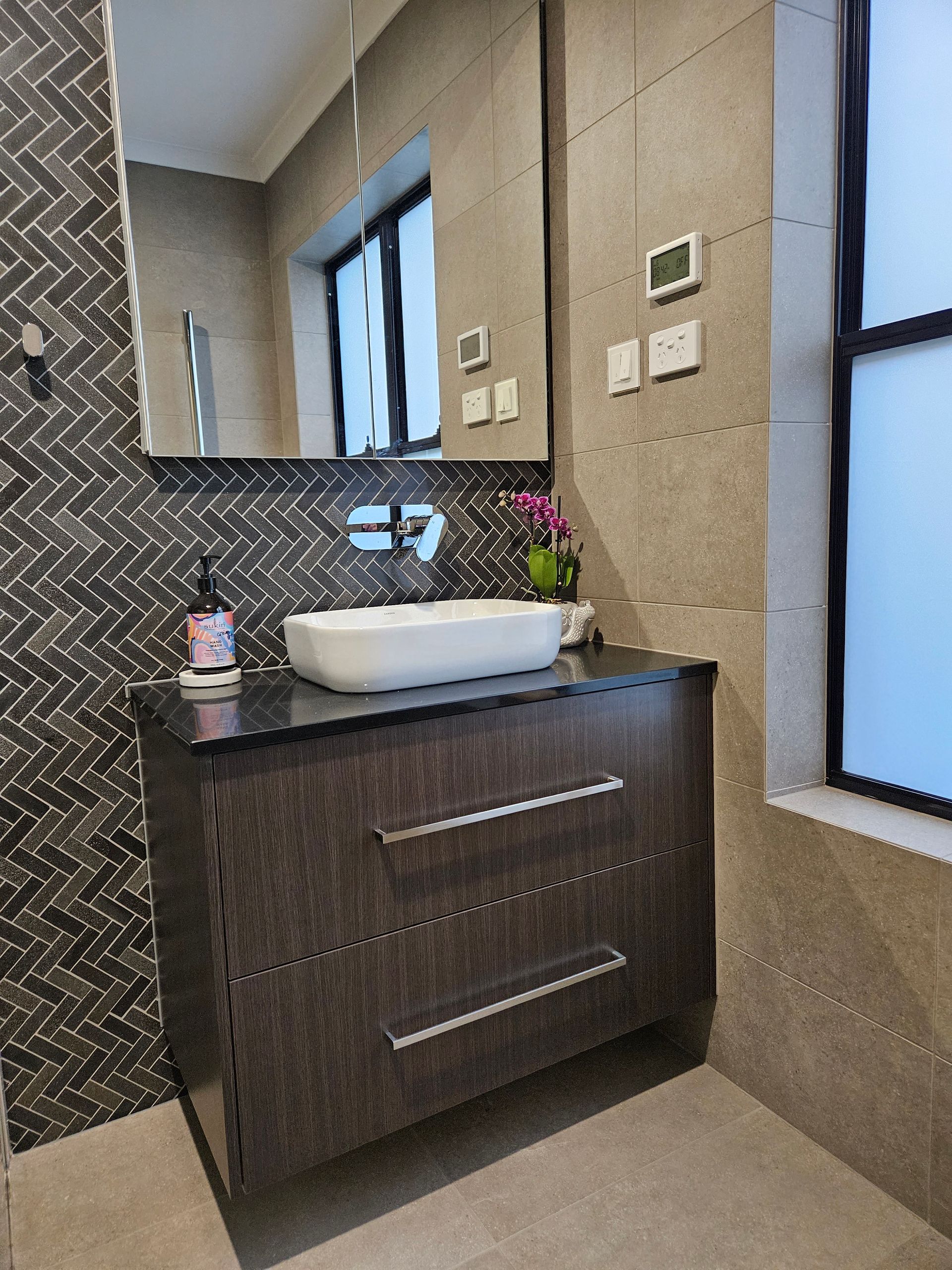A bathroom with a sink , mirror and window