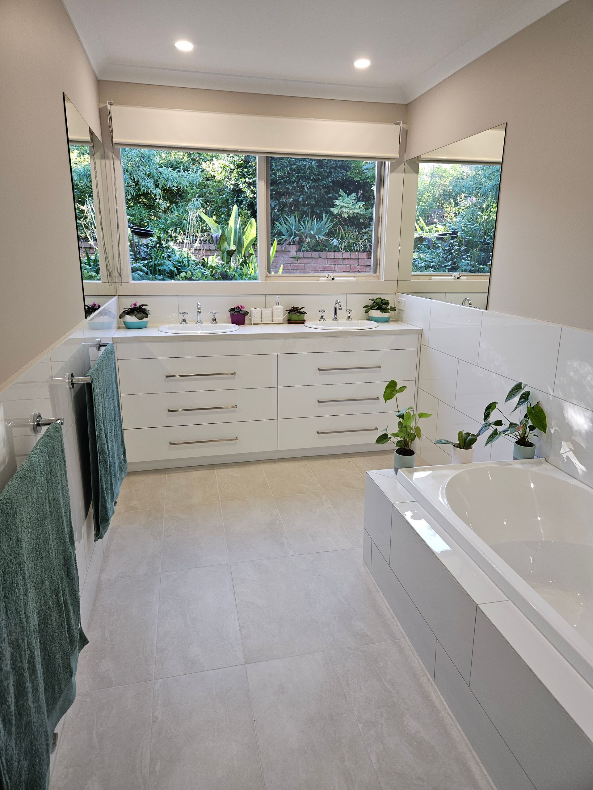 A bathroom with a tub , sink , mirror and window.