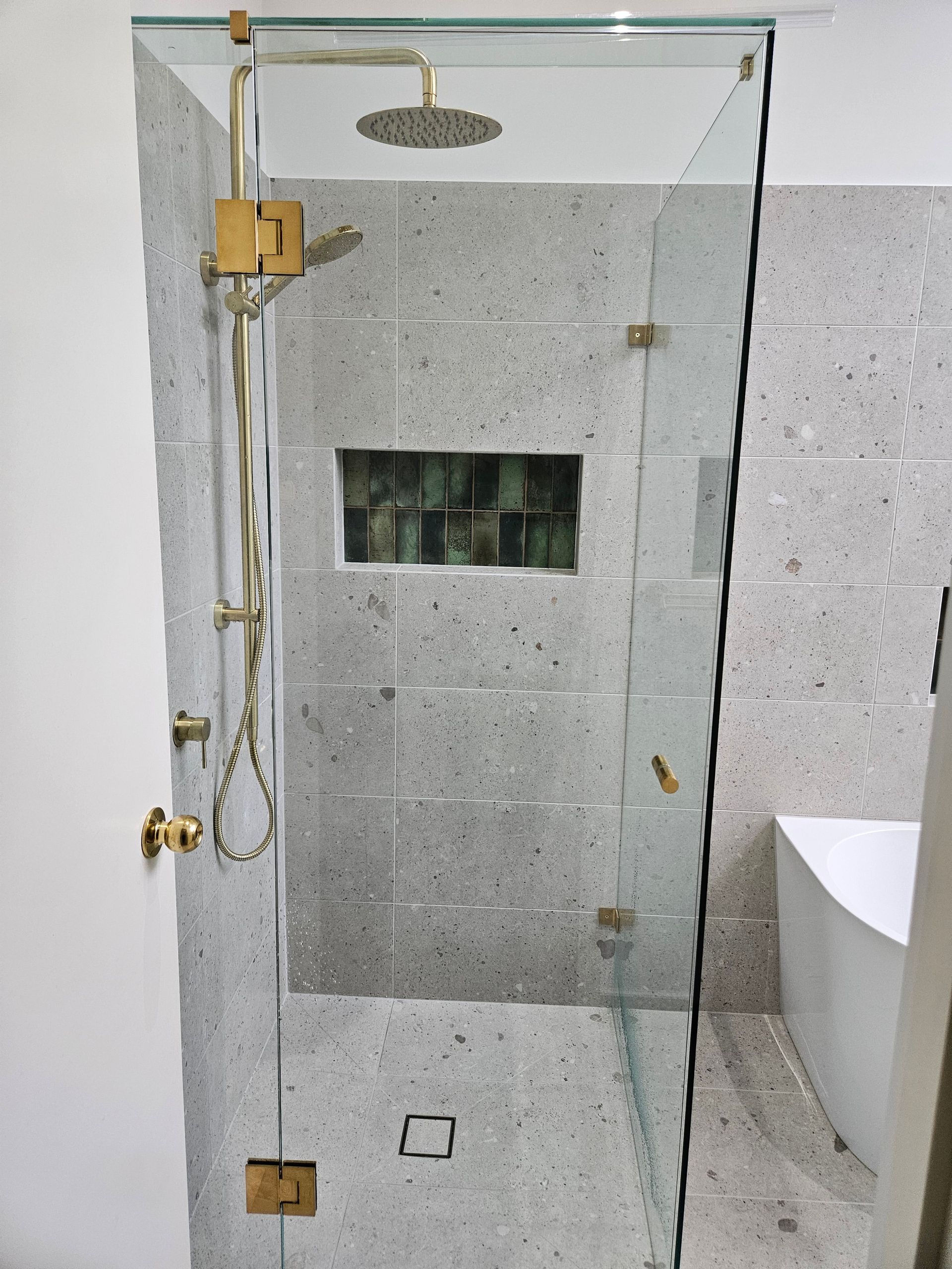 A bathroom with a walk in shower with a glass door and a shower head.