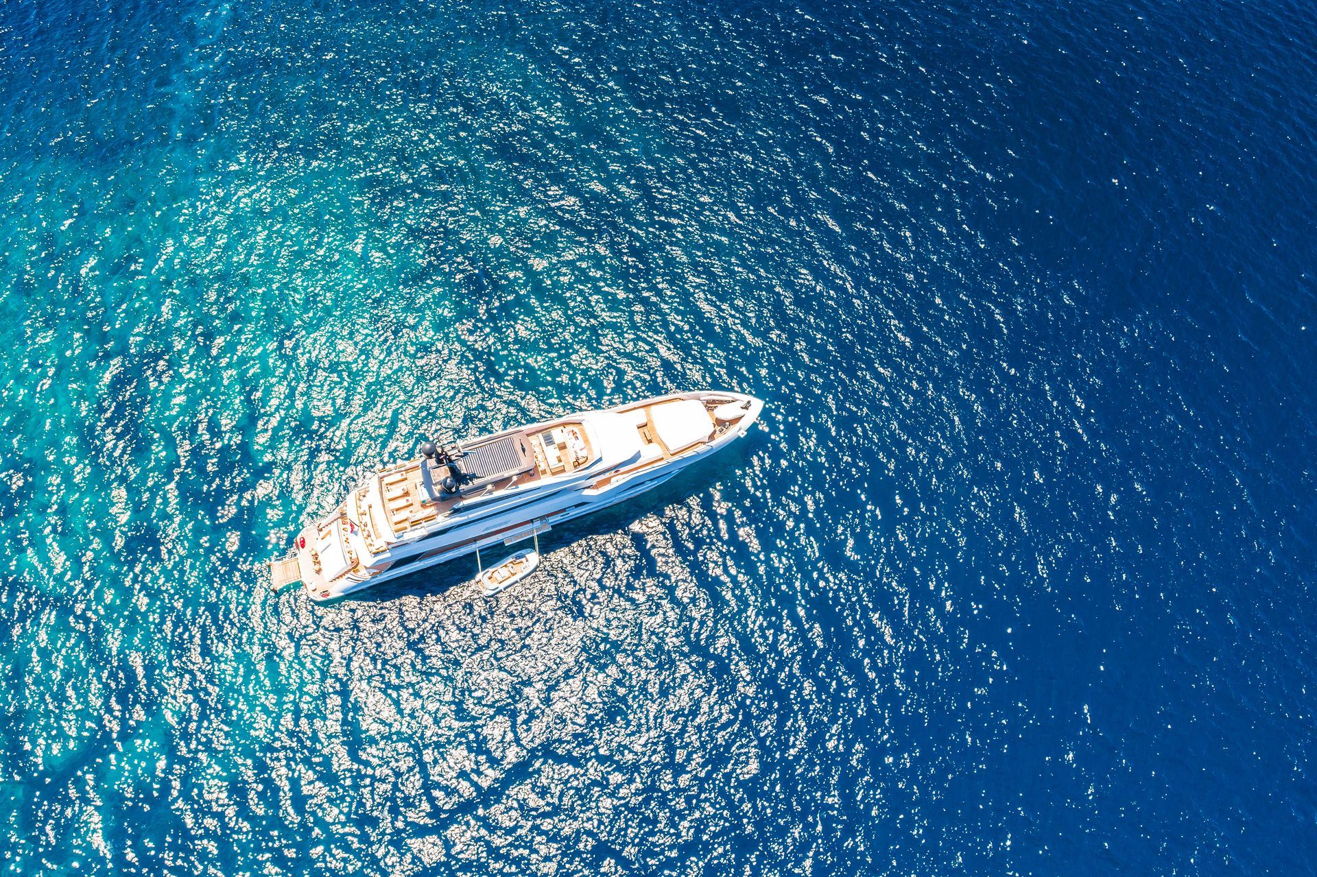 a large white superyacht is anchored in a tropical blue sea