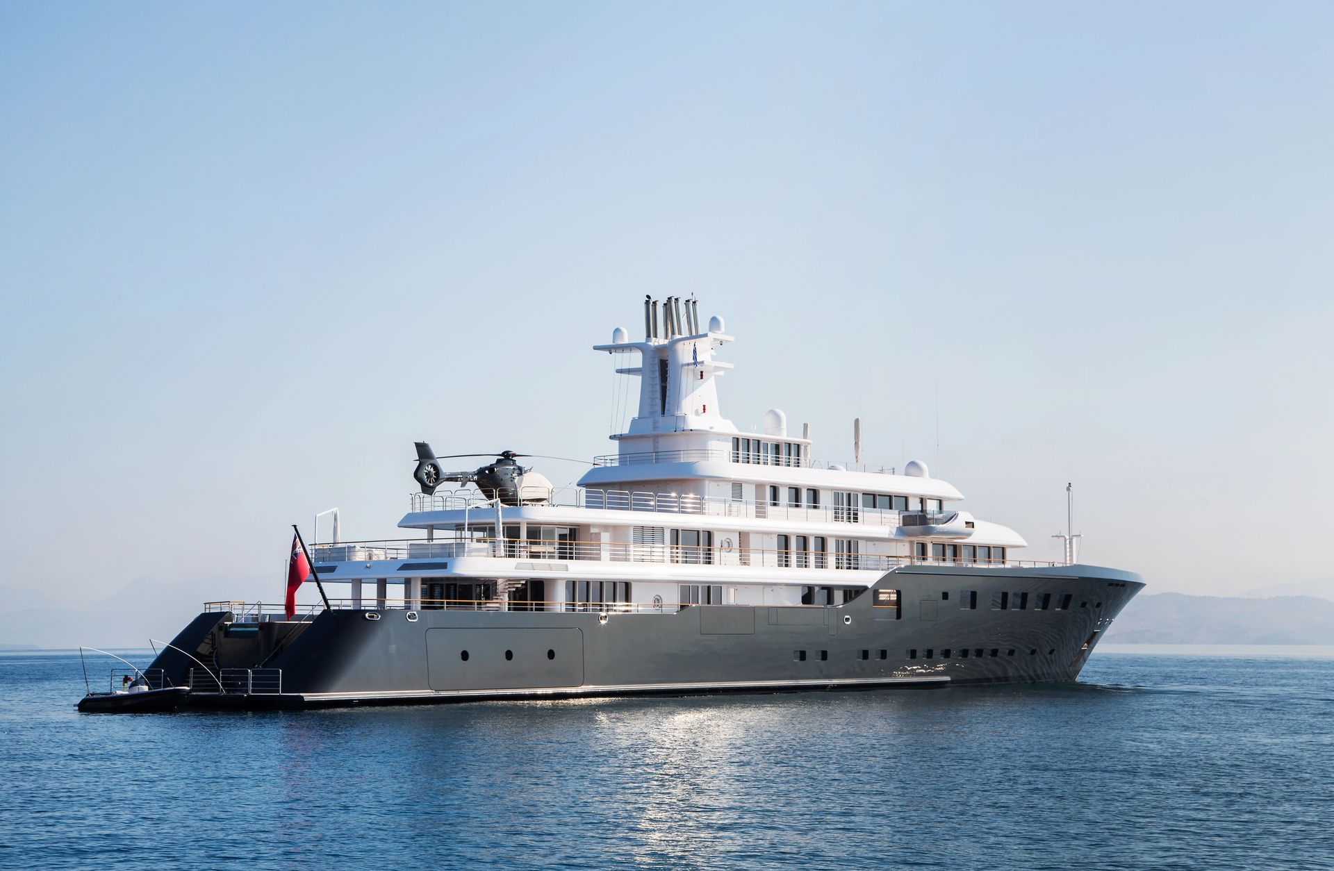 Superyacht with blue hull and Eurocopter on upper deck in calm seas