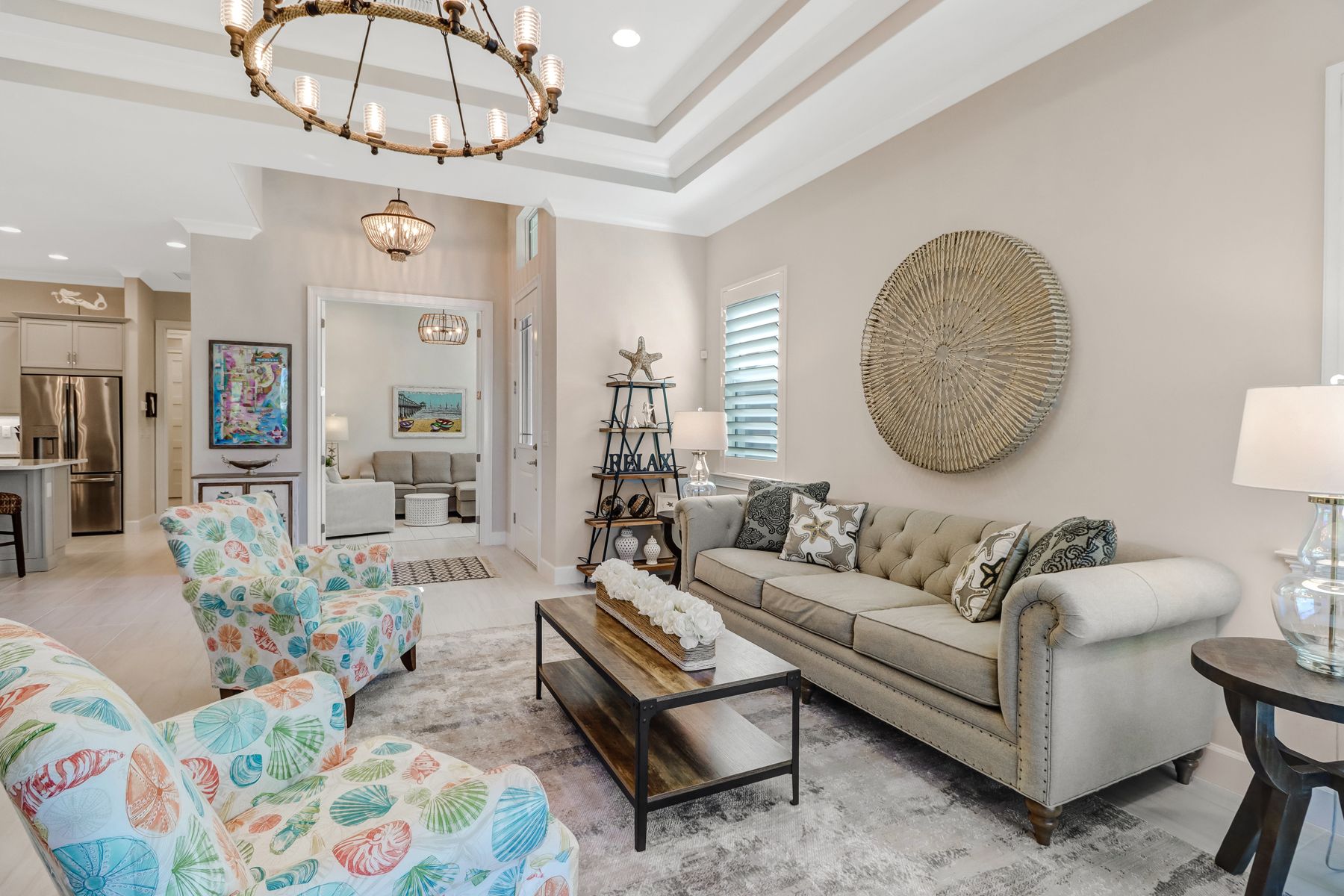 Elegant living room with floral chairs, beige sofa, glass coffee table, and chandelier lighting