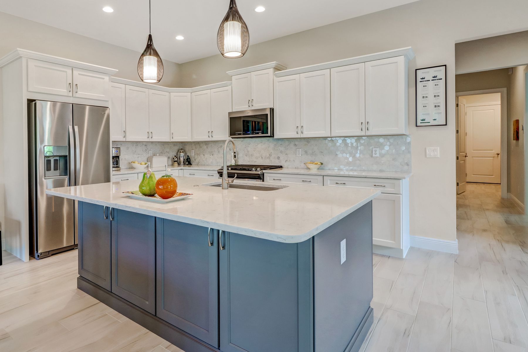 Modern kitchen with white cabinets, stainless appliances, blue island, and pendant lights