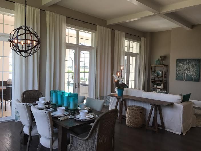 Elegant dining room with set table, white chairs, turquoise vases, and covered buffet table by tall windows