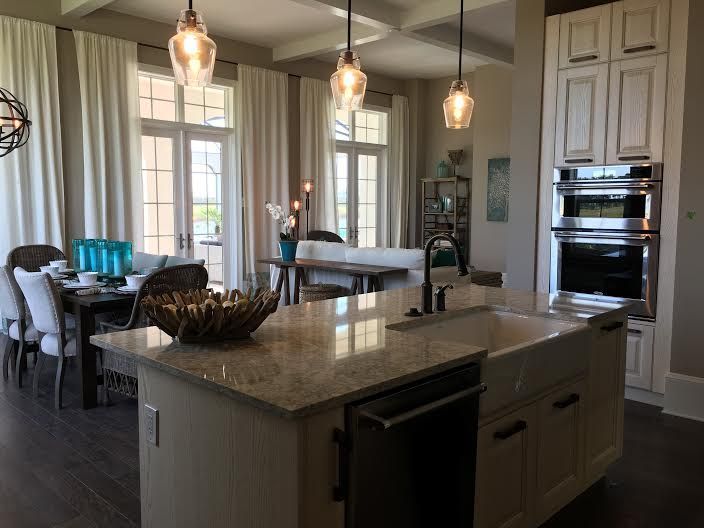 Bright modern kitchen with island, pendant lights, and open dining area by windows