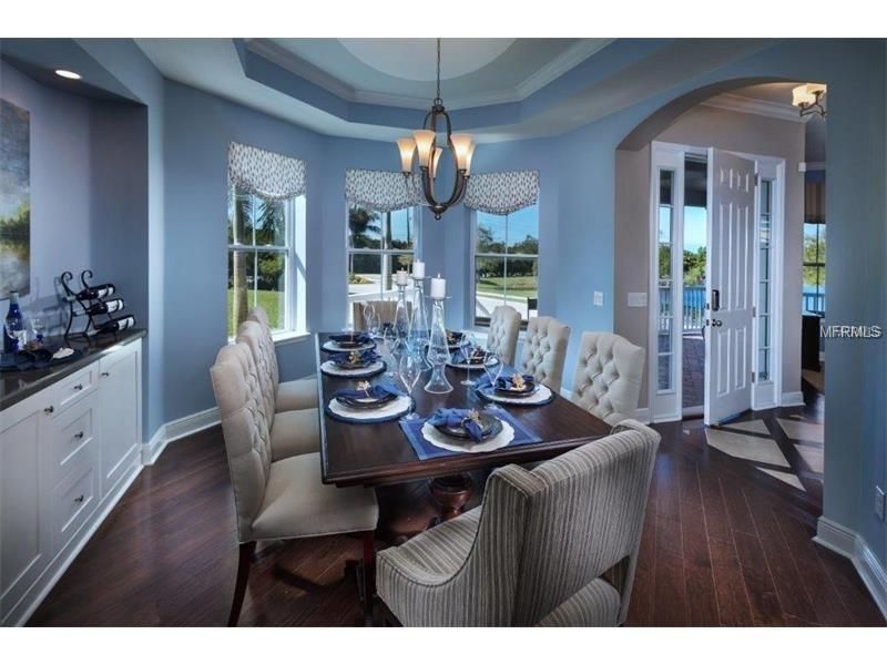 Elegant dining room with set table, chandelier, and large windows overlooking a waterfront view