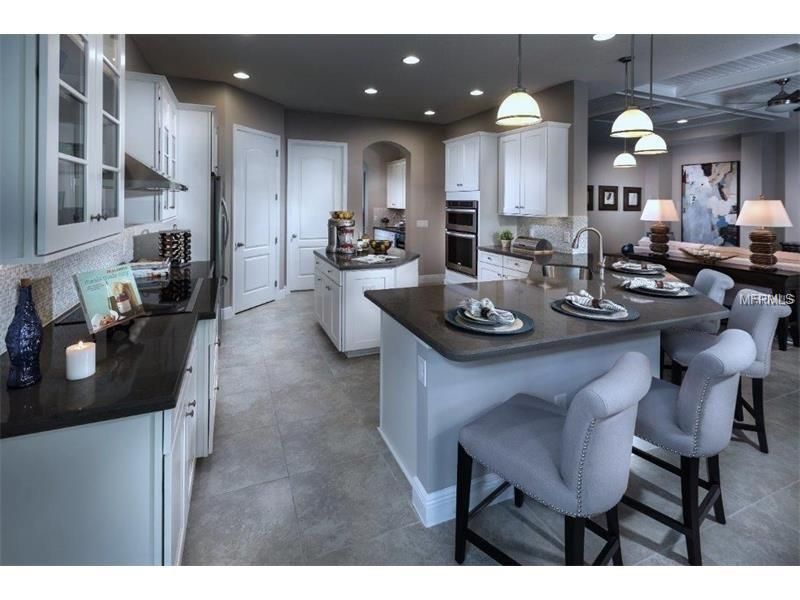 Bright modern kitchen with white cabinets, gray island, pendant lights, and barstools