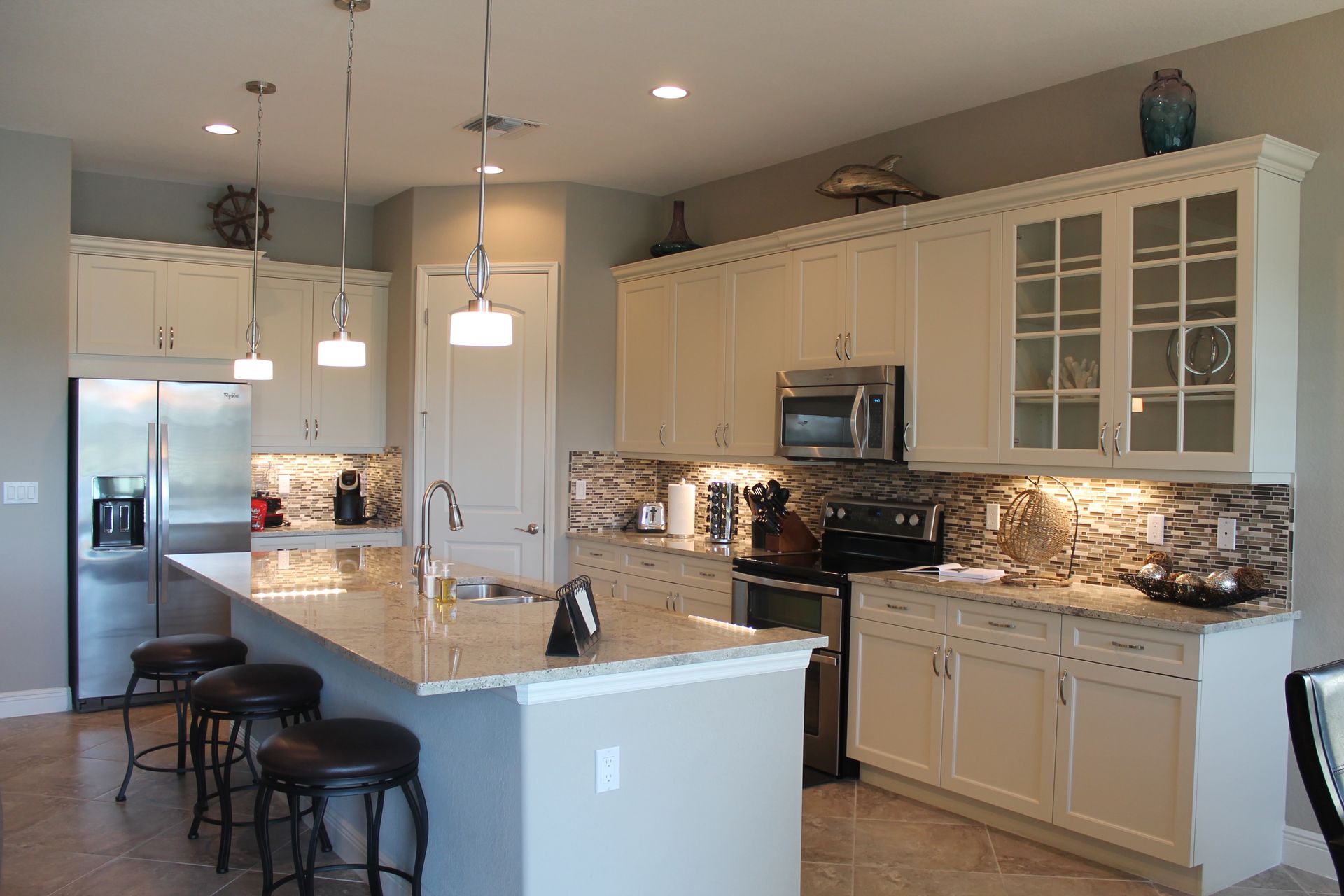 Bright modern kitchen with white cabinets, granite island, stainless appliances, and barstools