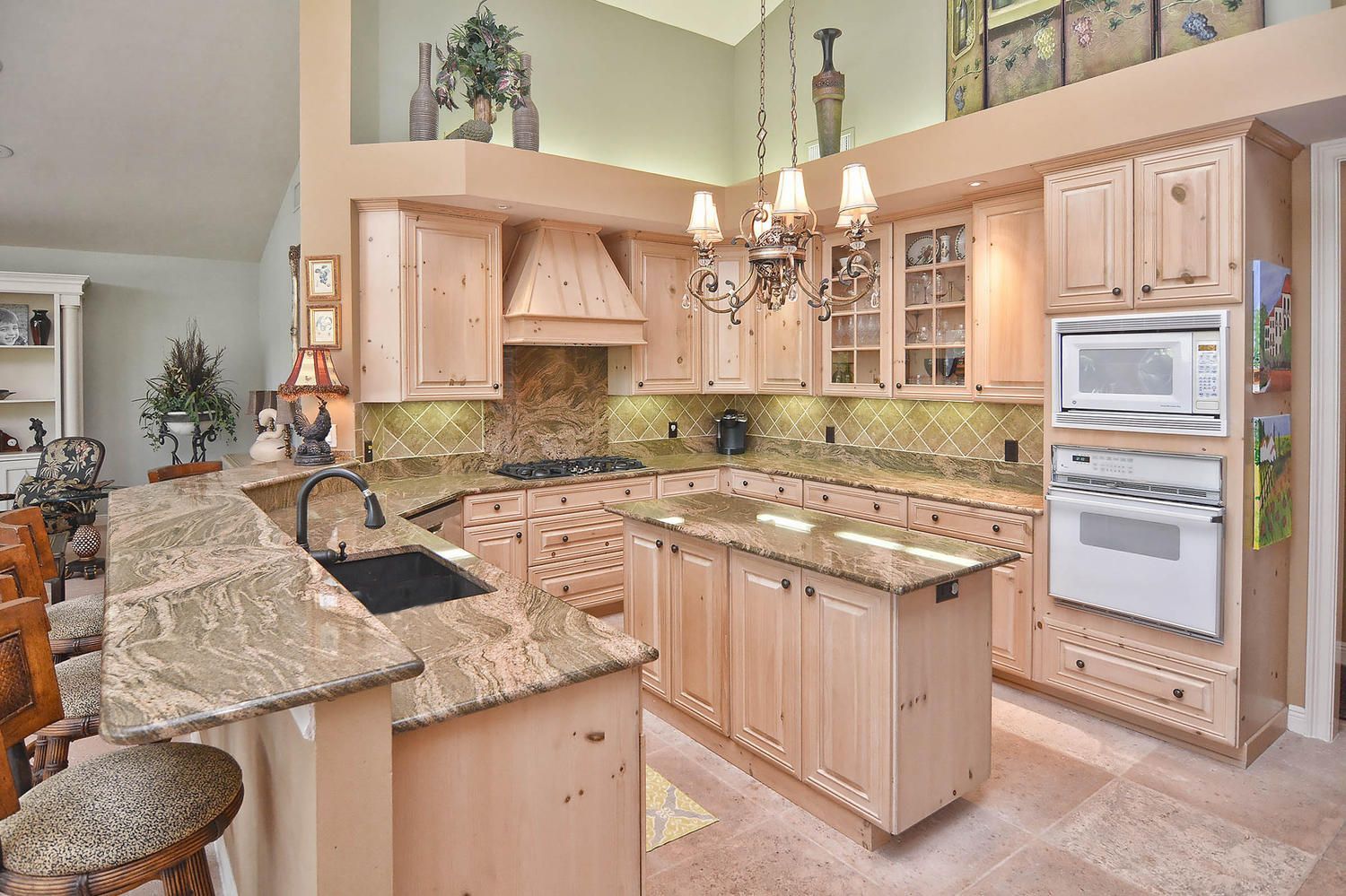 Bright kitchen with light wood cabinets, granite countertops, and a center island under warm lighting