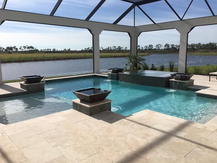 Covered patio with a rectangular swimming pool overlooking a calm lake.