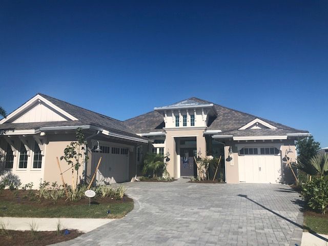 Single-story modern house with a three-car garage and paved driveway under a clear blue sky