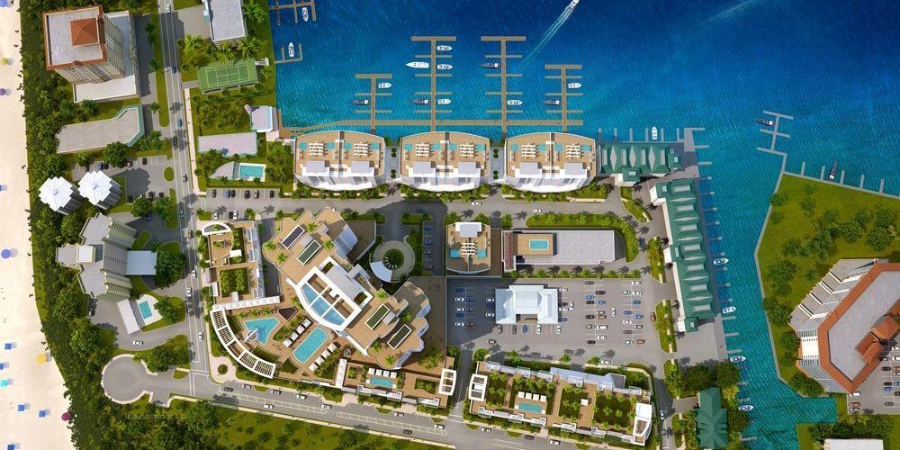 Aerial view of a waterfront marina with boats, docks, buildings, and turquoise water