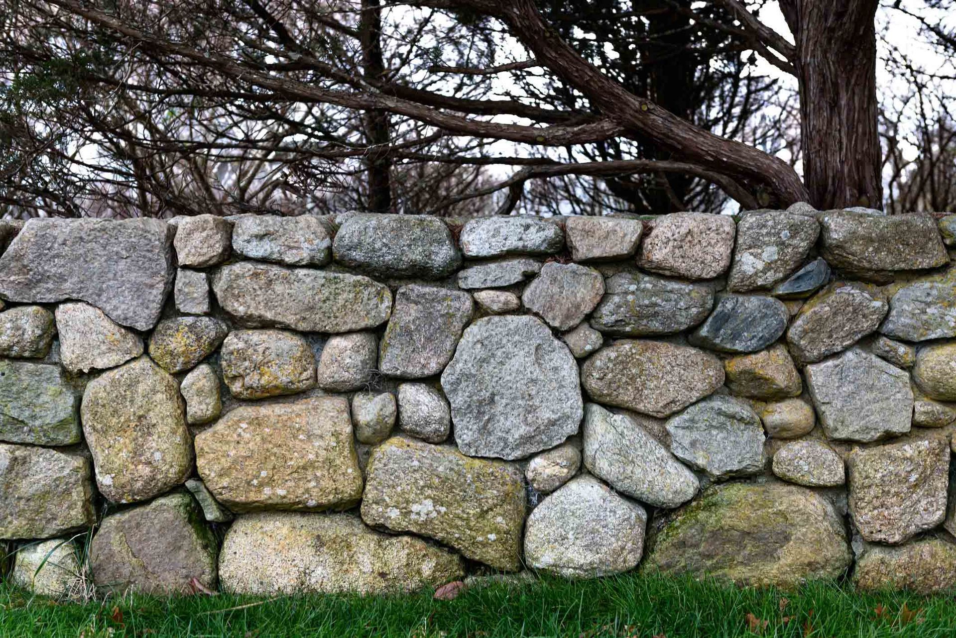 A Stone Wall with Trees in The Background | Cranbourne, VIC | Cranbourne Fencing Pty Ltd