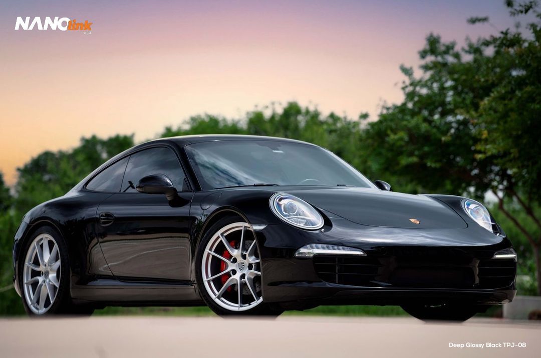 Black Porsche sports car parked outdoors with a sunset background.