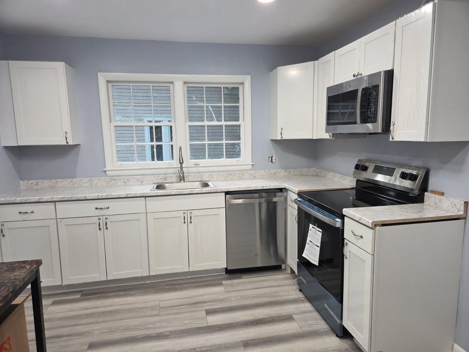 White kitchen with stainless steel appliances, light countertops, and blue walls.