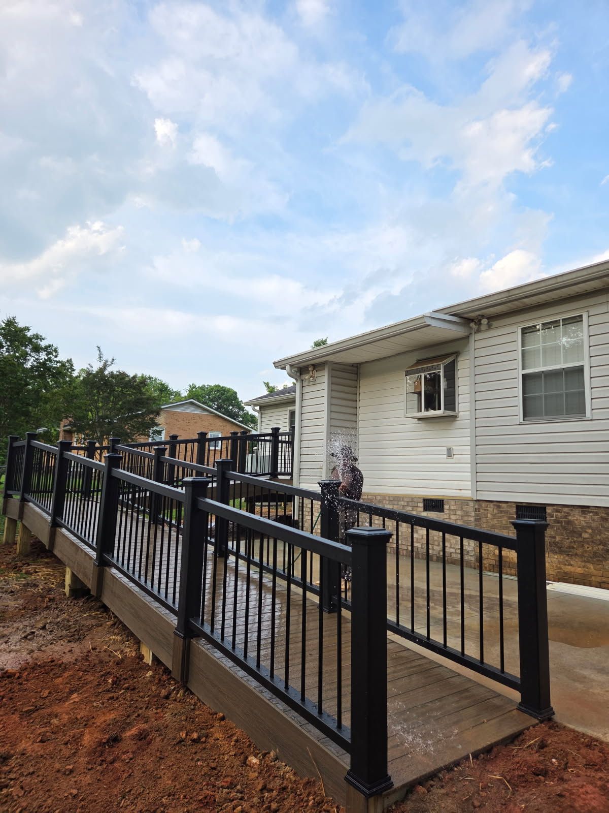 Ramp leading to a white building with black railings; cloudy sky.