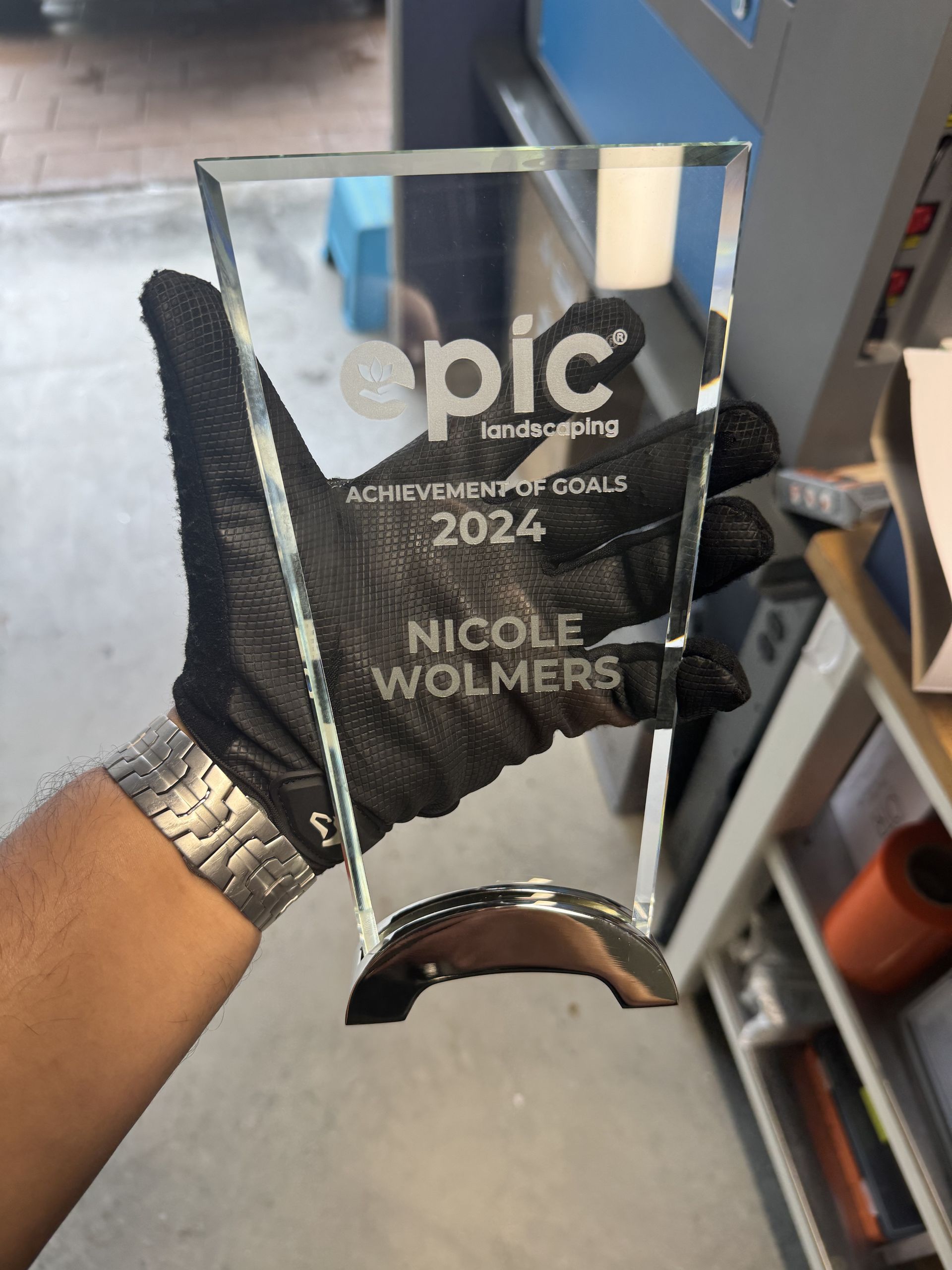 Person wearing a black glove holds a glass award. Award says 