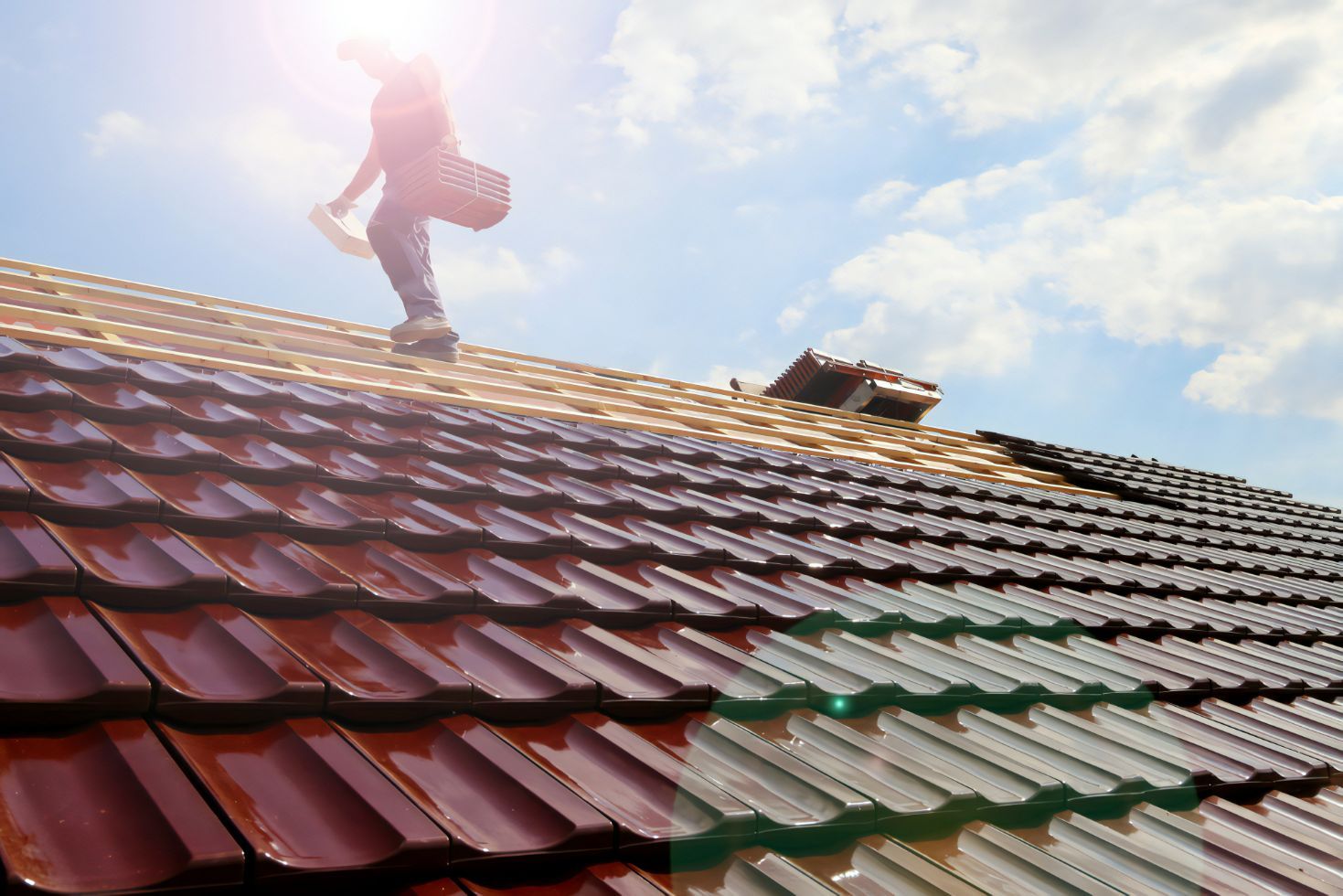 A Man is Standing on Top of a Tiled Roof — Stormguard Roofing In Caloundra West, QLD
