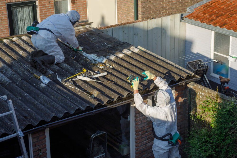 Two Men in Protective Suits Are Working on a Roof — Stormguard Roofing In Redcliffe, QLD