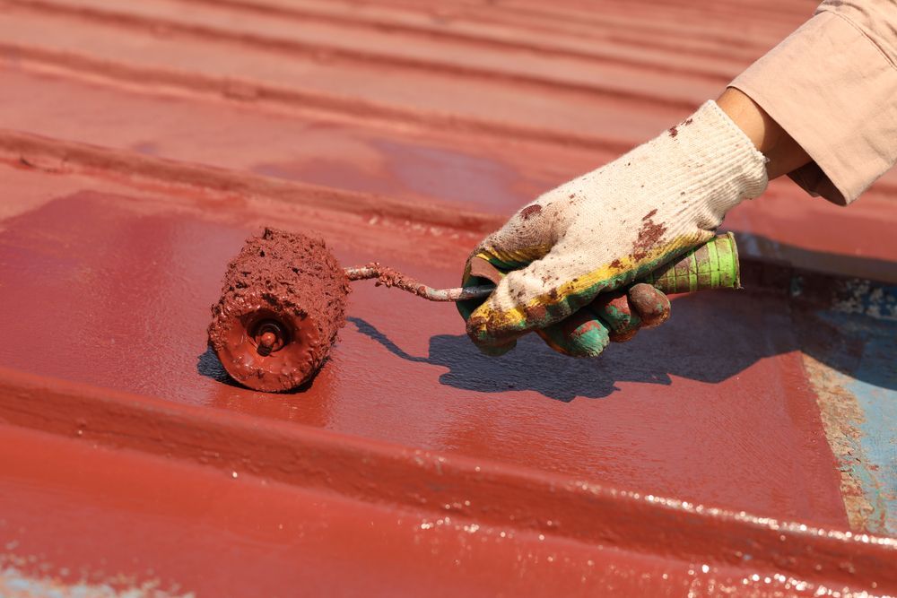 A Person is Painting a Roof With a Roller — Stormguard Roofing In Gympie, QLD