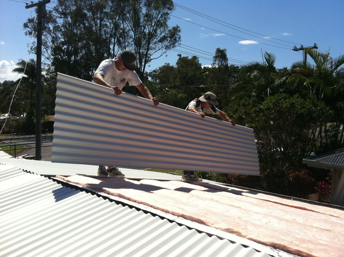 A roofer replacing metal sheets on a residential home