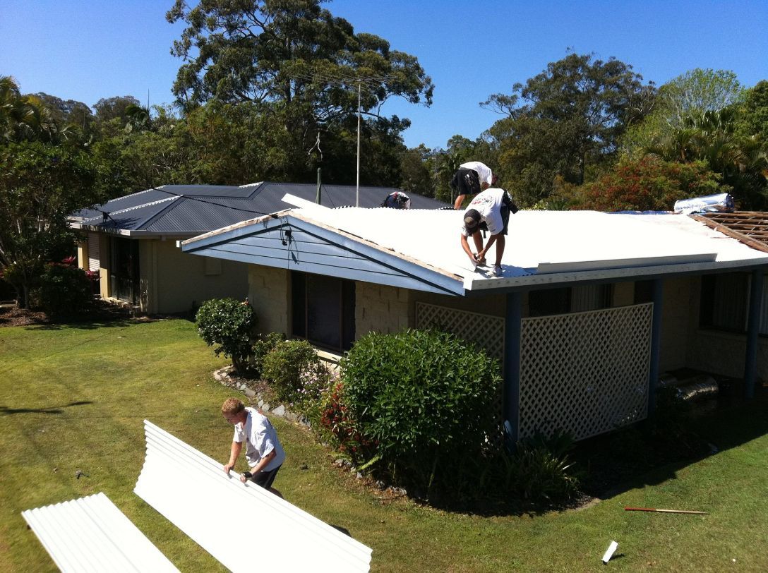Two Men Are Working on the Roof of a House — Stormguard Roofing In Caloundra West, QLD