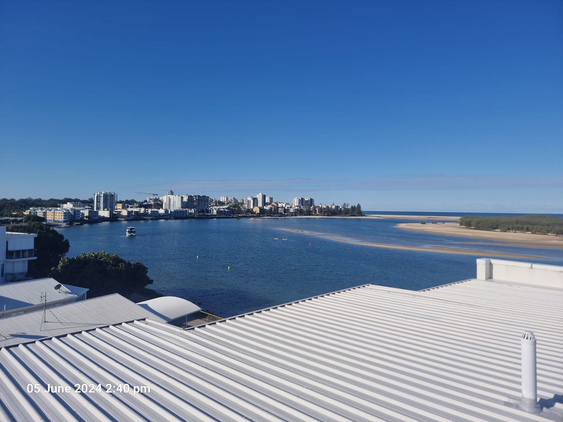 Coastal Bay and Beach With City Skyline Under a Clear Blue Sky — Stormguard Roofing In Caloundra West, QLD